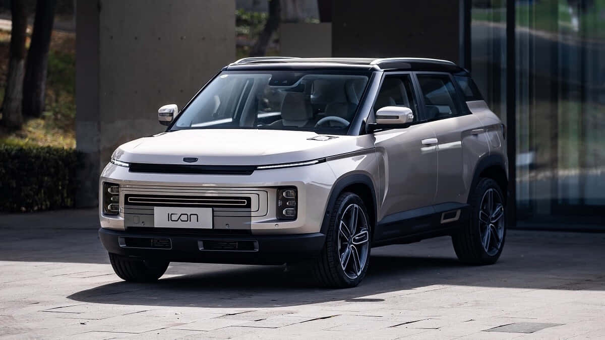  壁紙 — 一輛時尚的銀色SUV，採用現代棱角設計，停在玻璃建築旁的鋪砌庭院中。