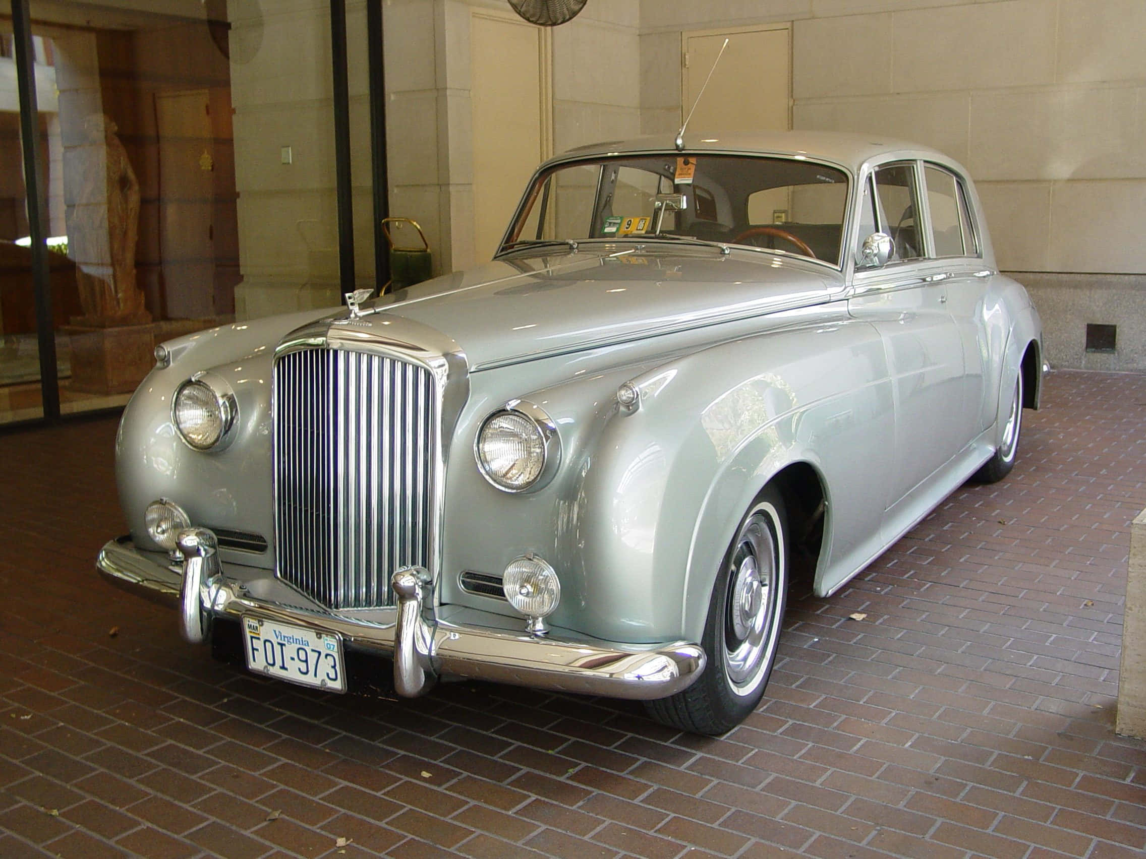 Bentley S2 桌布 壁紙 — 一輛時尚的銀色復古車帶有鍍鉻裝飾，在磚地上的室內燈光下閃閃發光。