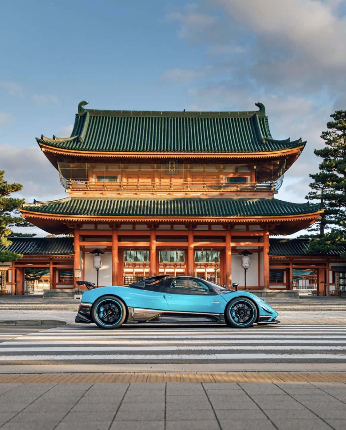 Pagani Zonda Tricolore 桌布 壁紙 — 一架流線型青綠色超跑停泊在傳統日本寺廟前，寺廟有綠色瓦頂，天空清澈湛藍。