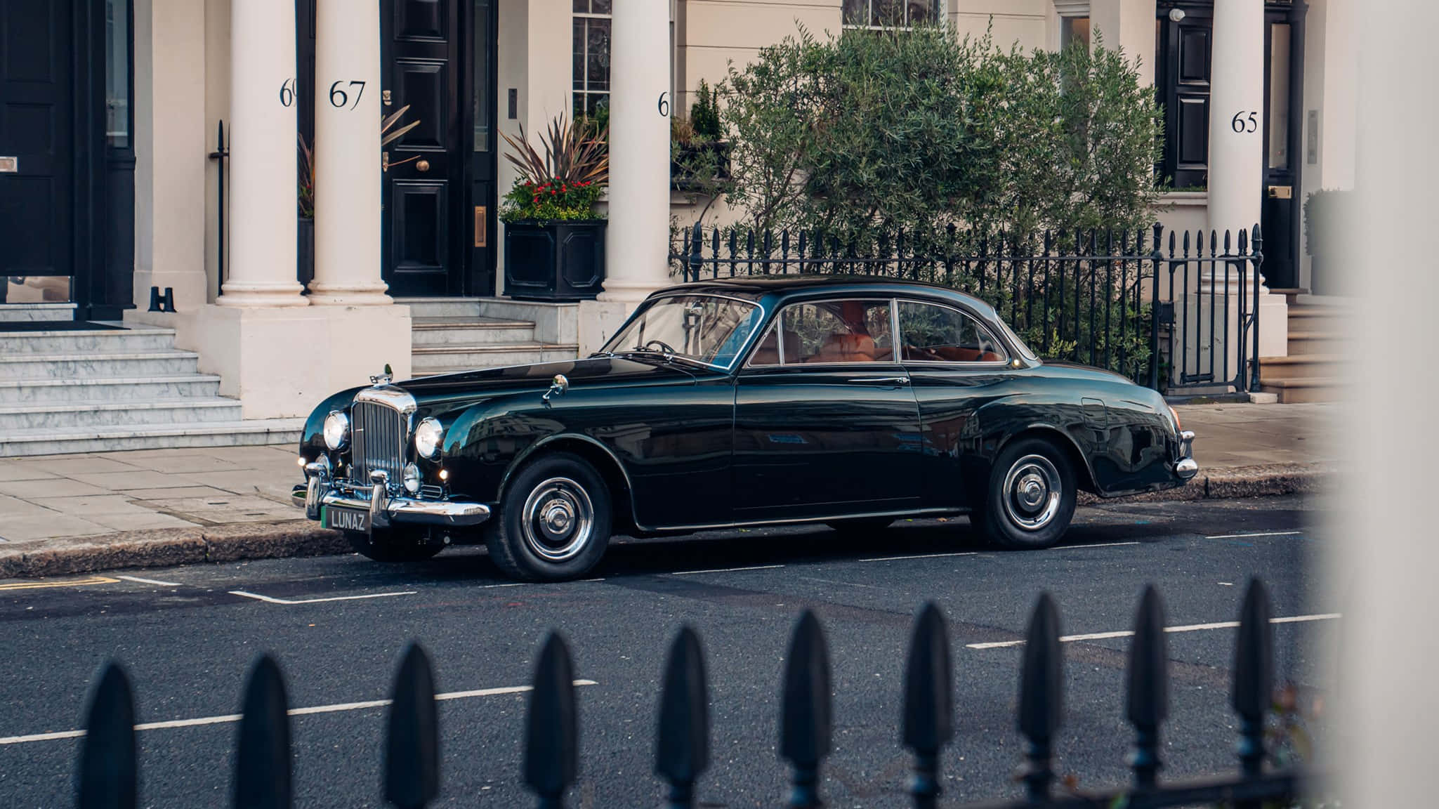 Bentley S2 桌布 壁紙 — 一架時尚的復古綠色賓利房車停泊在寧靜的住宅街道上，街道兩旁是優雅的聯排別墅和黑色鍛鐵圍欄。