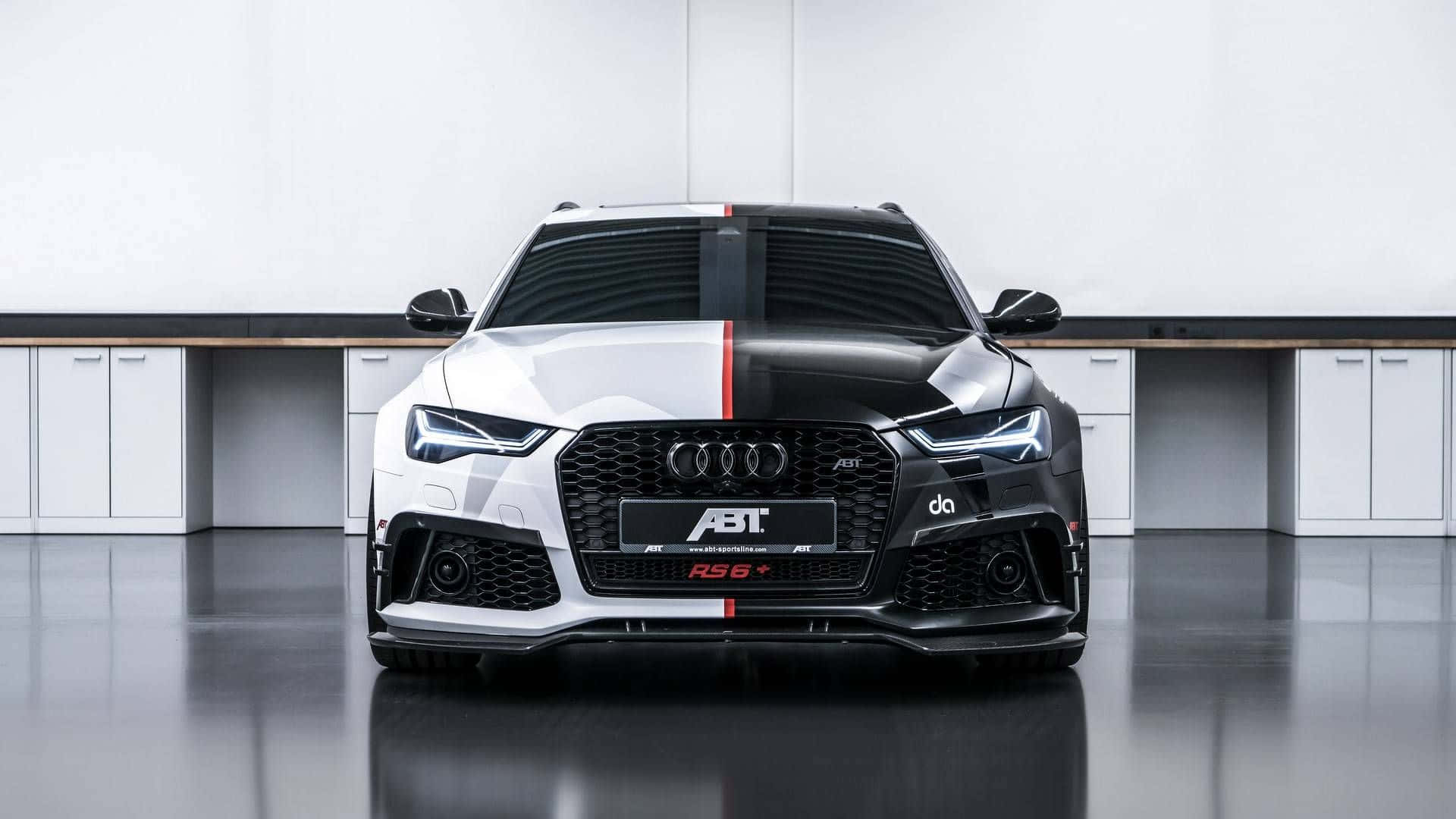Audi Rs6 桌布 壁紙 — 一輛時尚的白黑ABT Audi RS6，帶有紅色賽車條紋，正面朝前停放在極簡白色車庫中，地板具有反射效果。