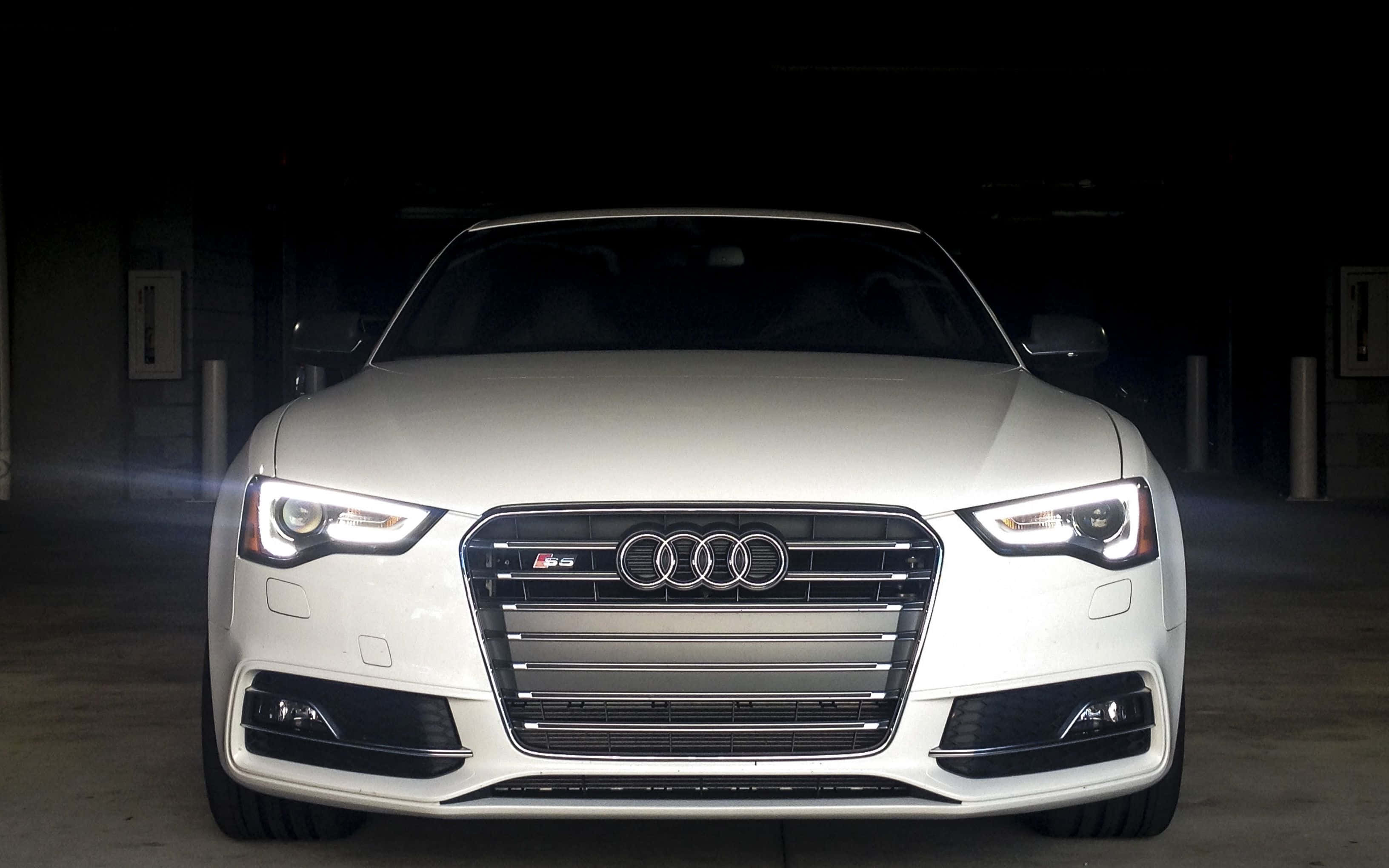 Audi S5 桌布 壁紙 — 一輛時尚的白色奧迪S5跑車在黑暗的地下停車場中，在戲劇性的聚光燈下閃閃發光。