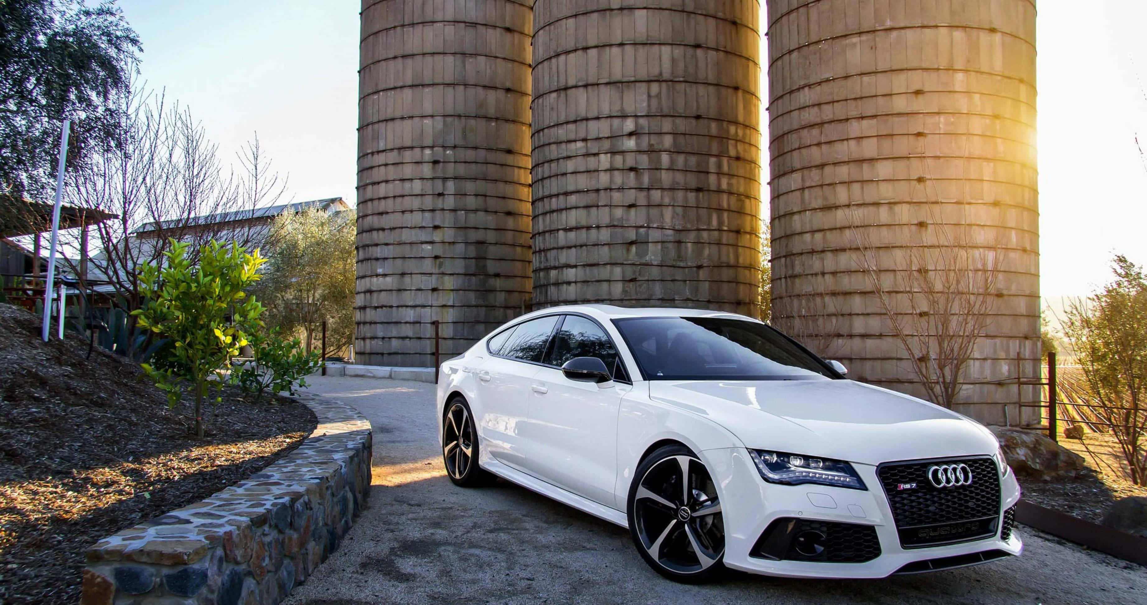 Audi A4 桌布 壁紙 — 一架時尚的白色奧迪跑車停泊在沐浴在金色日落光線中的高聳木製穀倉前。