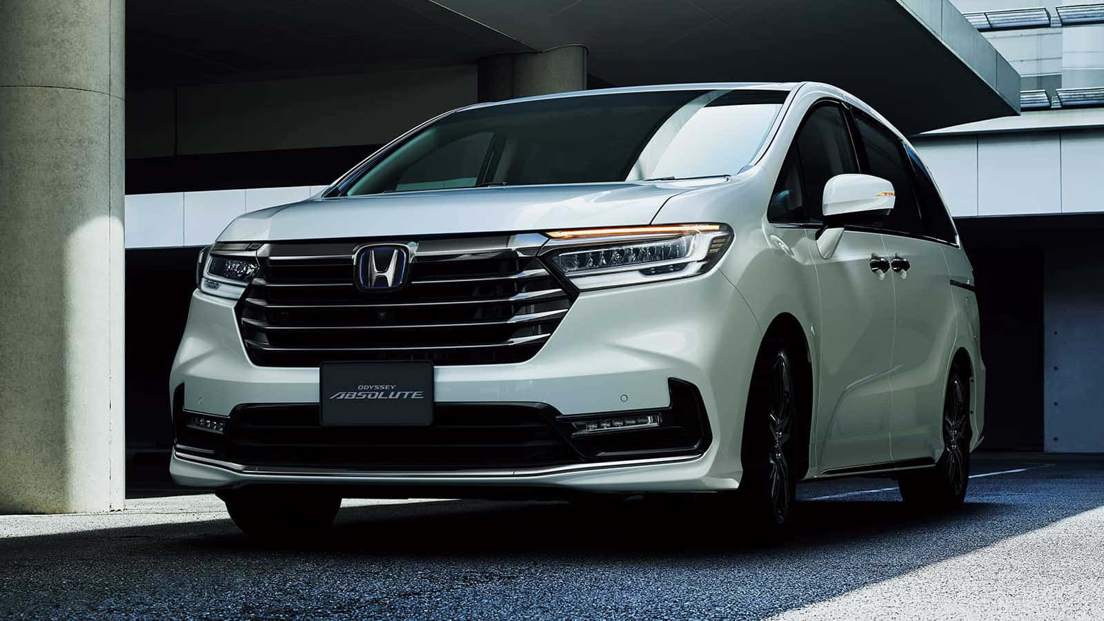 Honda Odyssey 桌布 壁紙 — 一架時尚的白色本田Odyssey Absolute小型貨車停泊在現代混凝土結構下，帶有銳利的陰影。