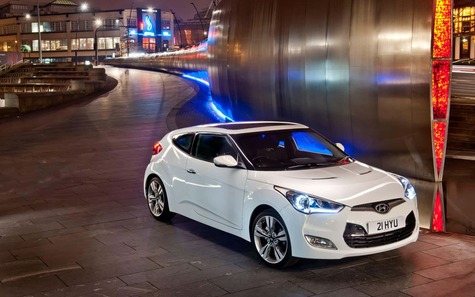 Hyundai Veloster 桌布 壁紙 — 一輛時尚的白色現代Veloster在夜間濕潤的城市街道上，在霓虹燈下閃耀，帶有動態模糊軌跡。