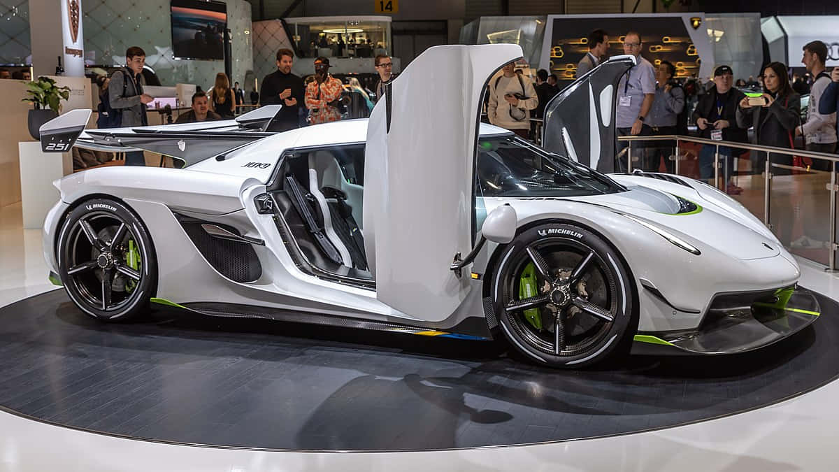  壁紙 — 一架白色流線型Koenigsegg超跑，剪刀門打開，在車展上展出，周圍有觀眾。