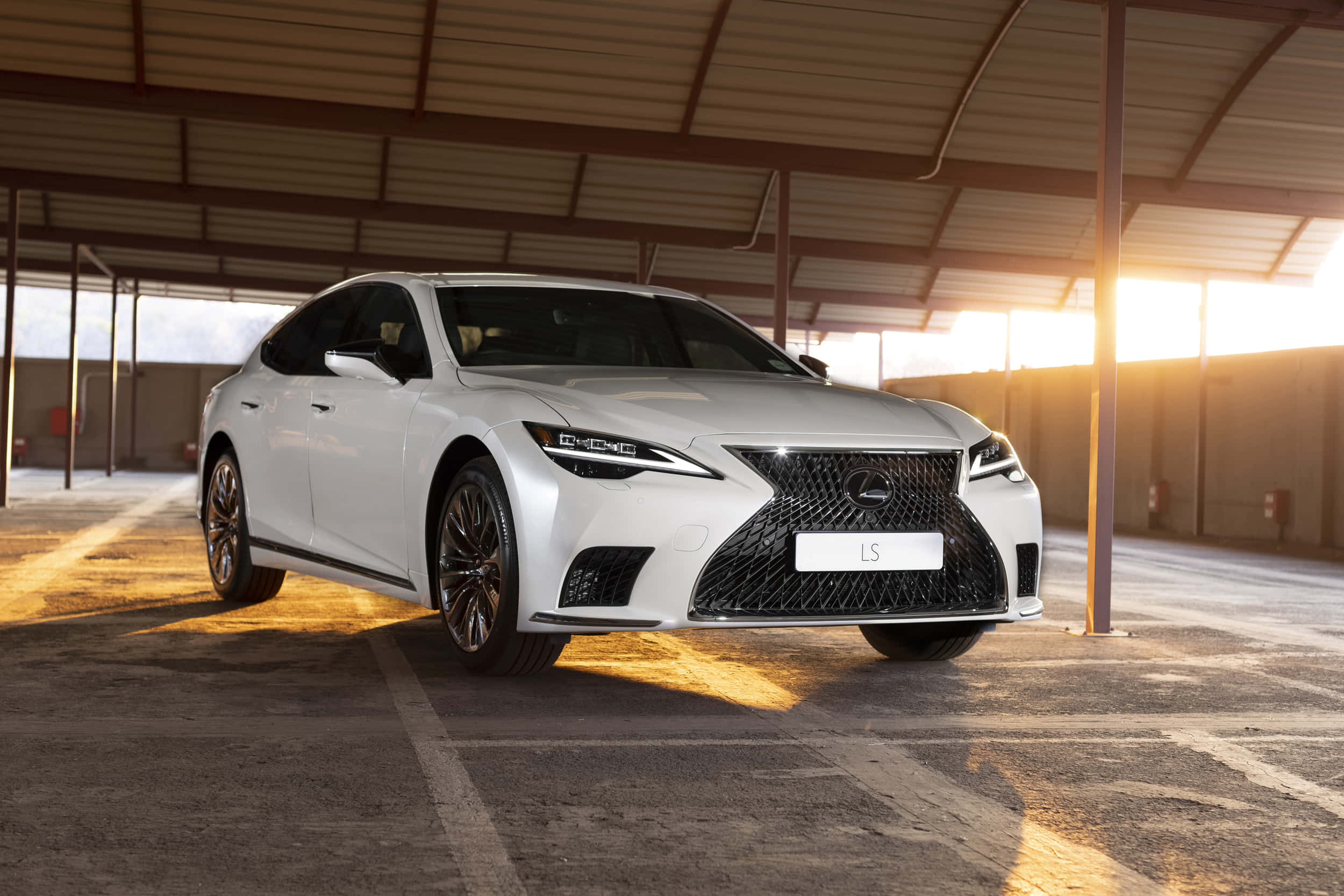 Lexus Ls 500 桌布 壁紙 — 一輛時尚的白色Lexus LS轎車在寬敞的工業車庫中，在金色夕陽下閃閃發光。