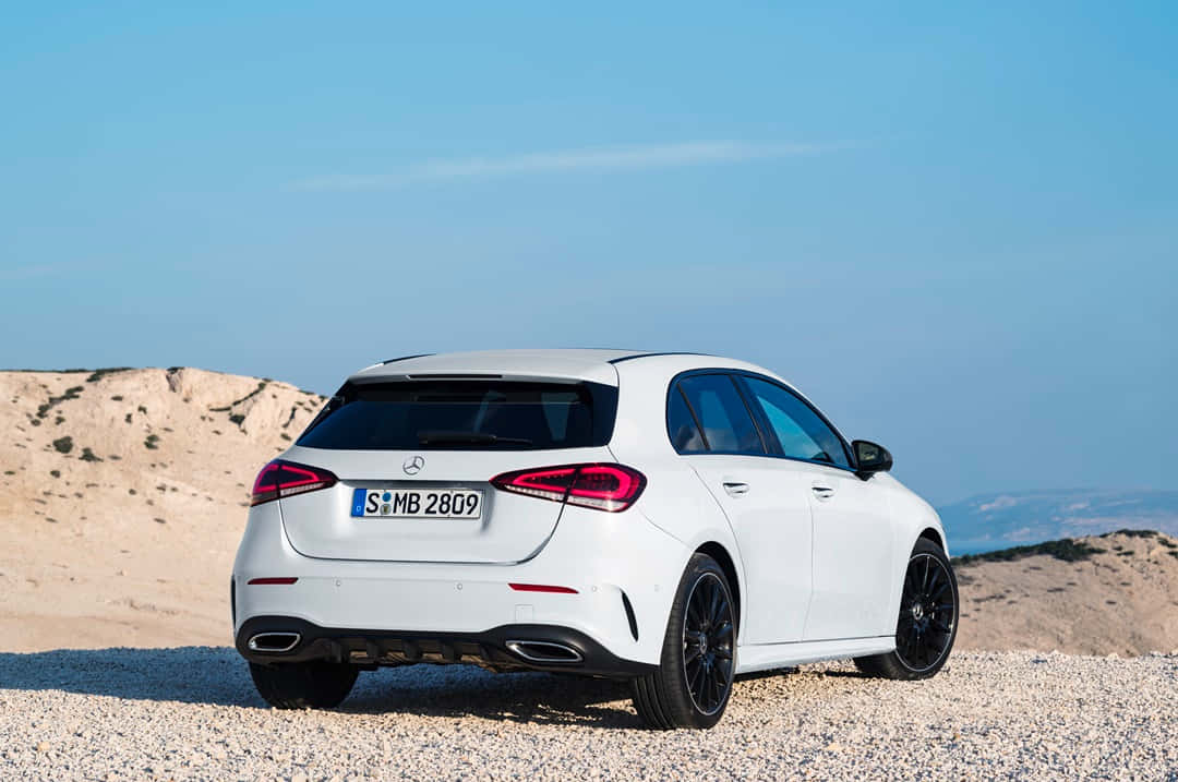 Mercedes Benz A-class 桌布 壁紙 — 一輛時尚的白色 Mercedes-Benz A-Class 掀背車停泊在陽光明媚的礫石平原上，遠山在清澈的藍天下。