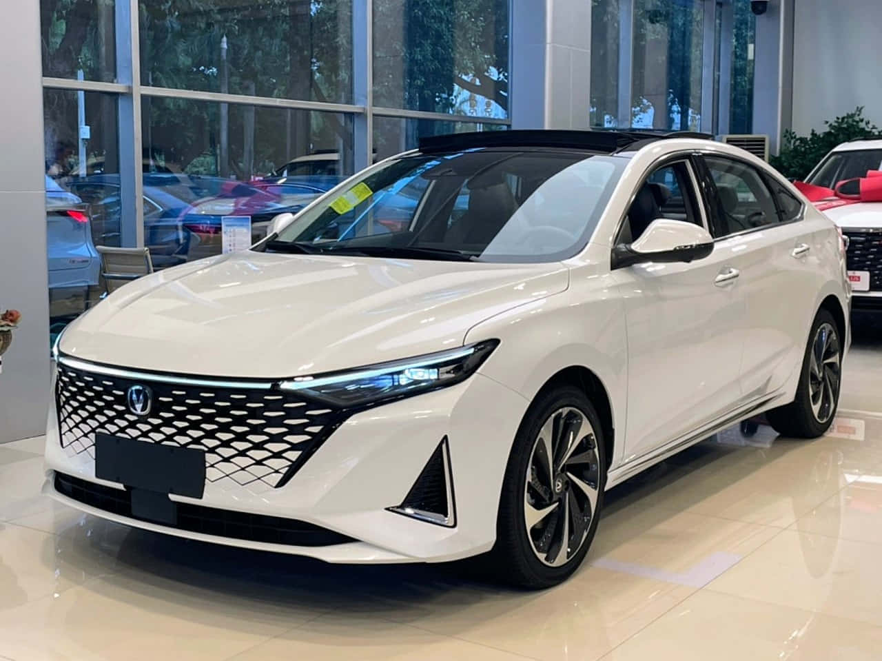  壁紙 — 一輛時尚的白色現代轎車在展廳燈光下閃閃發光，線條銳利，配以時尚合金輪圈。