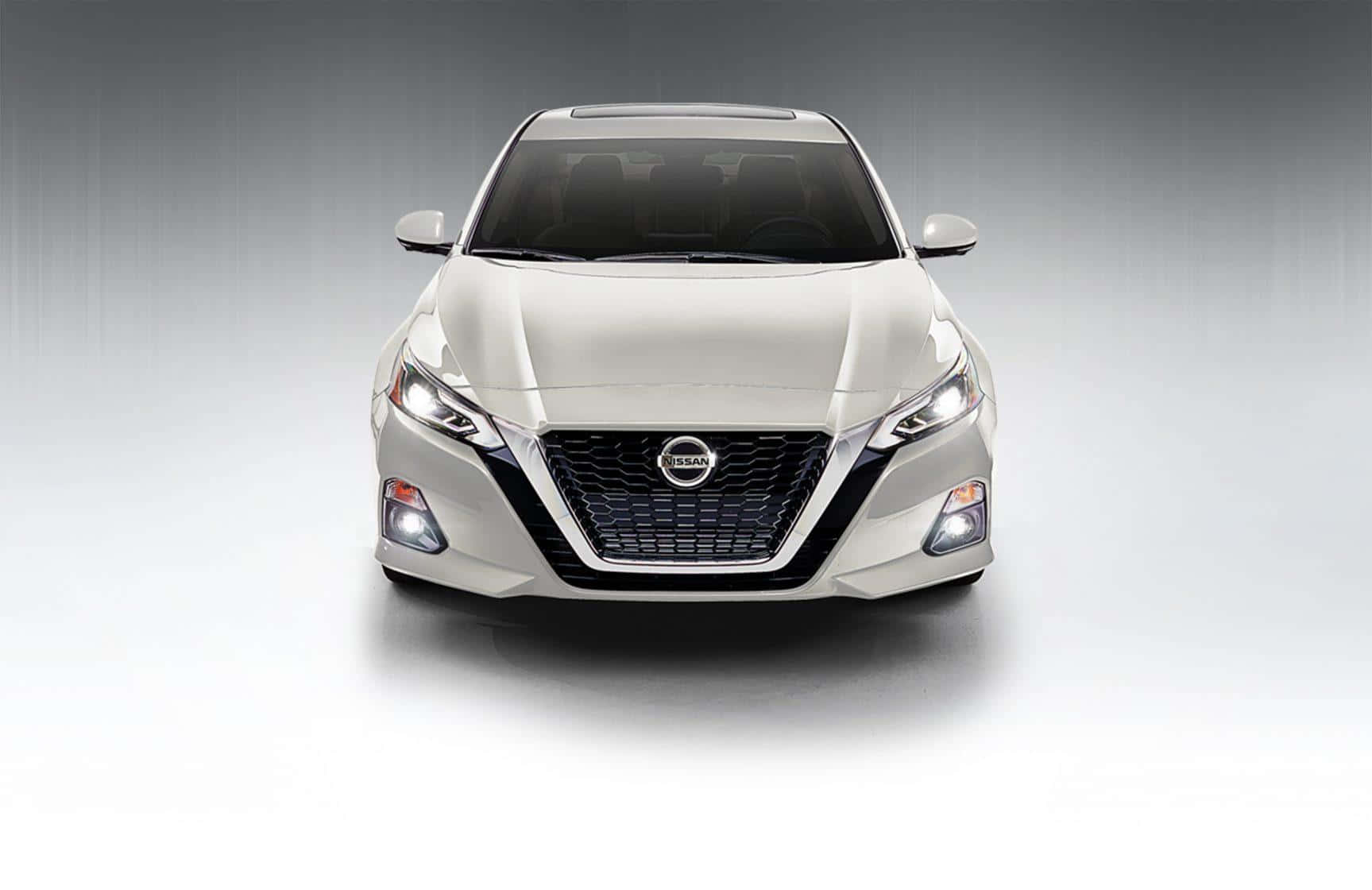 Nissan Altima 桌布 壁紙 — 一輛流線型白色日產房車正面朝前，配備銳利頭燈和醒目鬼面罩，背景為漸變工作室背景。