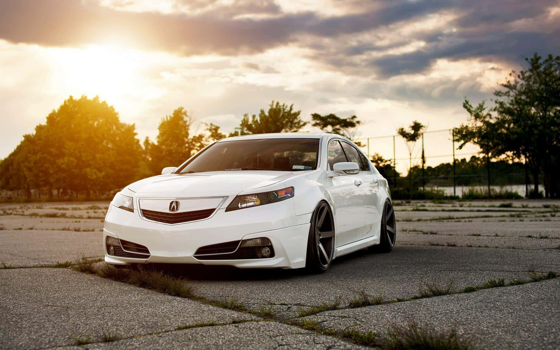 Acura Tsx 桌布 壁紙 — 一架流線型白色跑車停泊在裂開的路面上，背景是壯麗的日落天空，金光閃耀。
