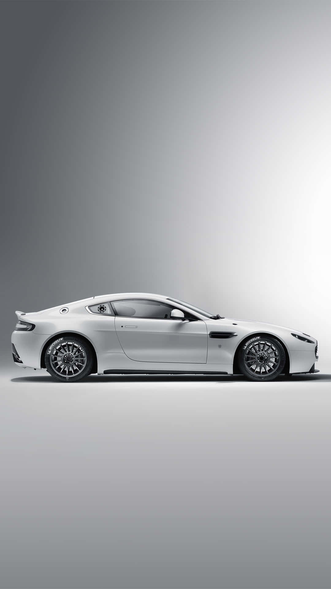 Aston Martin Vantage 桌布 壁紙 — 一輛時尚的白色跑車以側面輪廓展示，背景為極簡漸變灰色工作室背景。