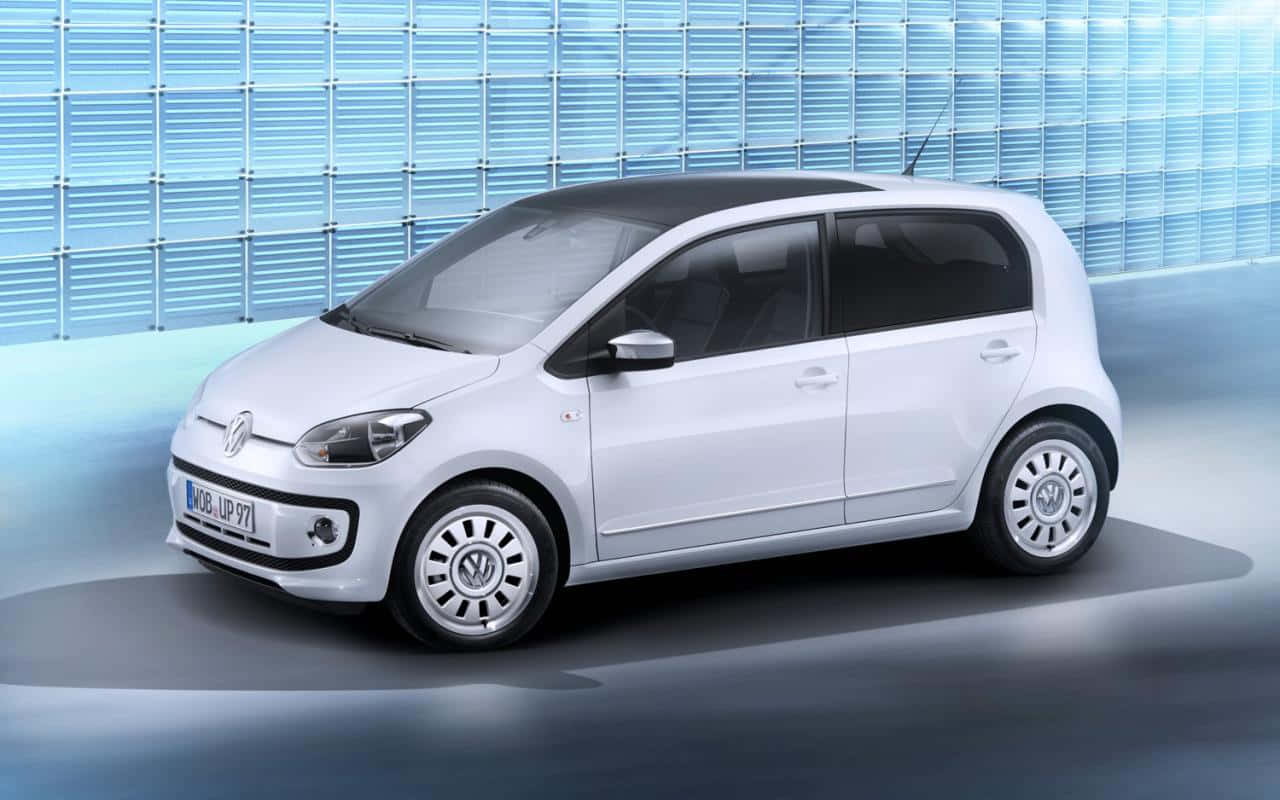  壁紙 — 一輛時尚的白色Volkswagen up! 緊湊型汽車，黑色車頂，在攝影棚燈光下停靠在藍色網格牆前。