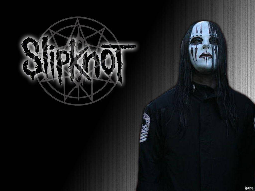 喬伊·喬迪森 Slipknot 壁紙 — 一個戴著面具的Slipknot樂隊成員站在深色紋理牆壁旁，旁邊是帶有發光邊緣的樂隊標誌。