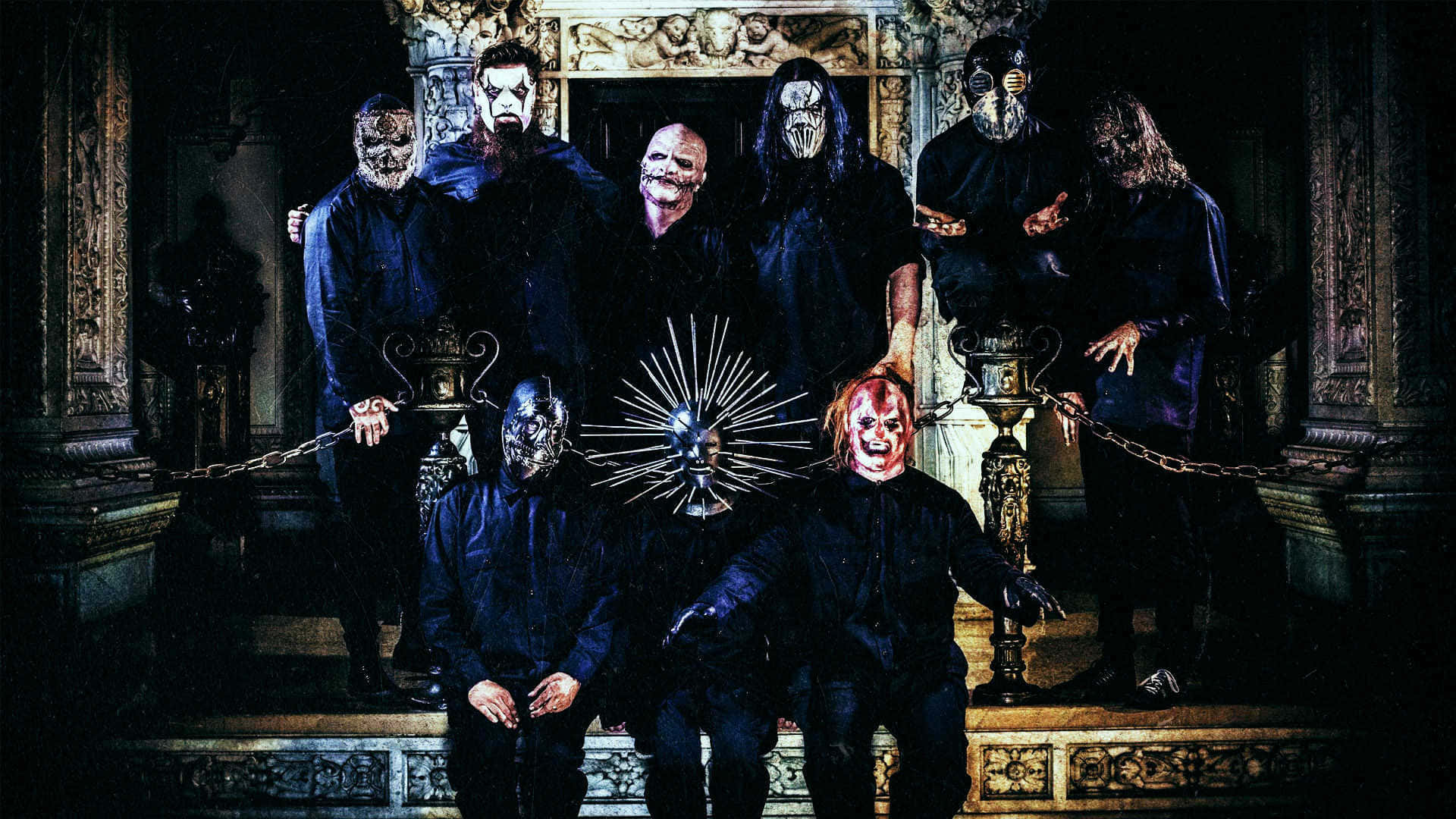 Slipknot於舞台演出 壁紙 — 一個戴著怪誕面具的樂隊在一個黑暗華麗的大宅大廳中，帶著鎖鏈和哥德式裝飾，戲劇性地擺姿勢。