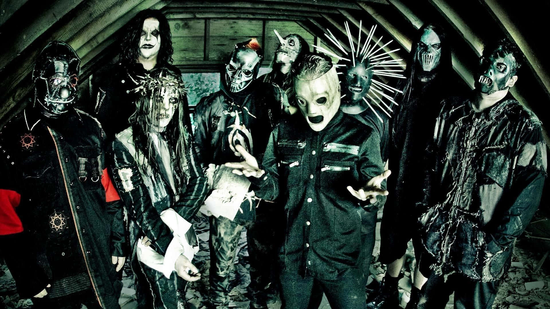 Slipknot桌面 壁紙 — 一群戴著面具、身穿暗黑哥德式服裝的音樂家在光線昏暗的木質閣樓中擺出威脅姿態。