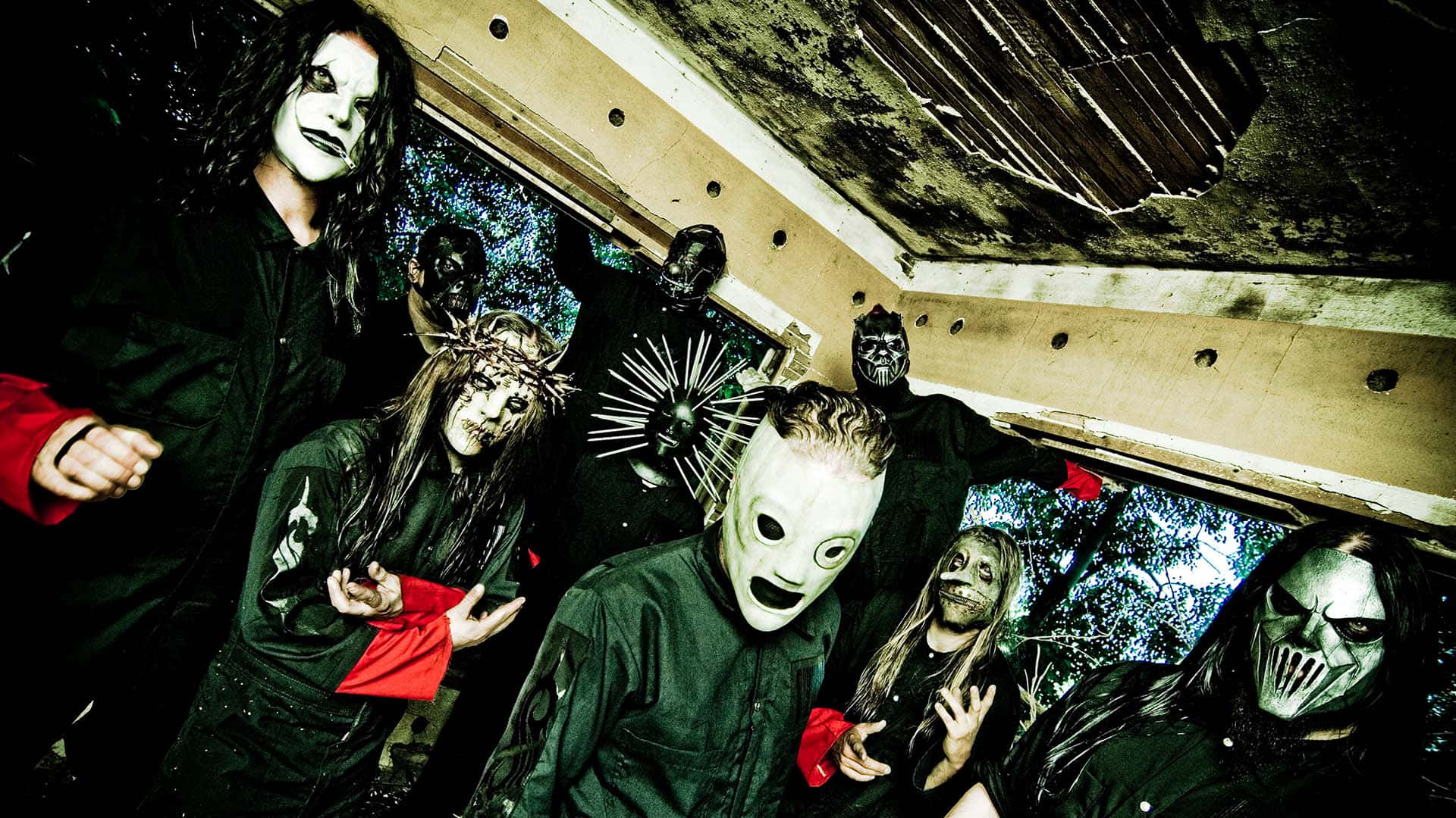 Slipknot桌面壁紙 壁紙 — 一群戴著面具、身穿深色衣服的音樂家在一個破舊、佈滿塗鴉的城市建築內戲劇性地擺姿勢。