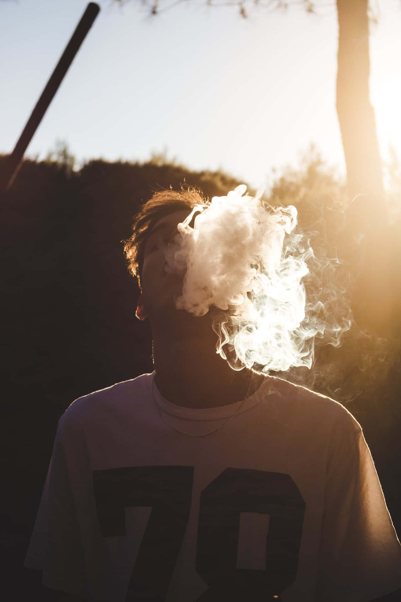 一個人在日落時呼出蒸氣，身後有剪影樹木。