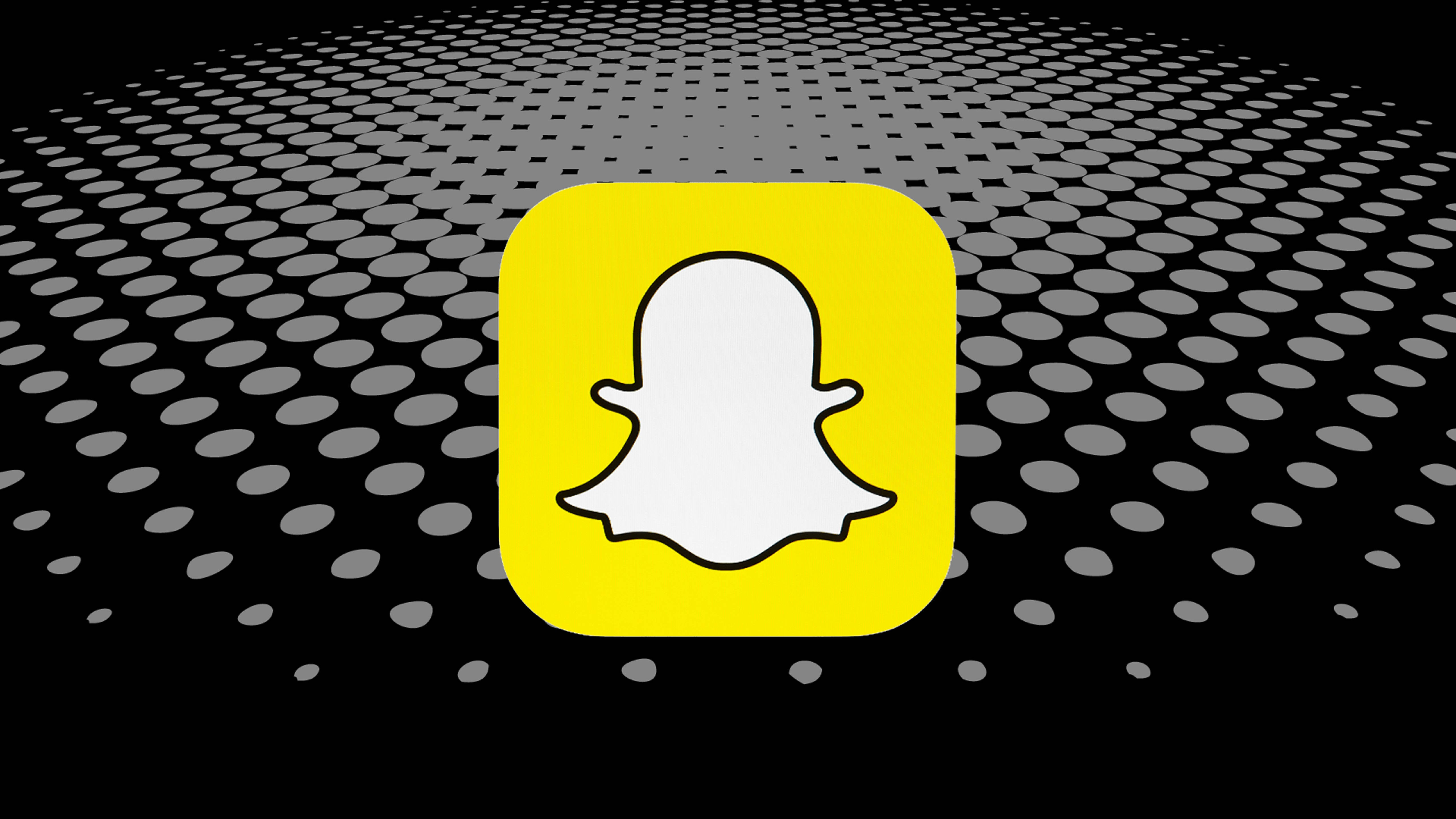 Snapchat圖標Zenly 壁紙 — 一個亮黃色的Snapchat鬼魂圖示，居中於黑色背景上，帶有後退的灰色圓點圖案。