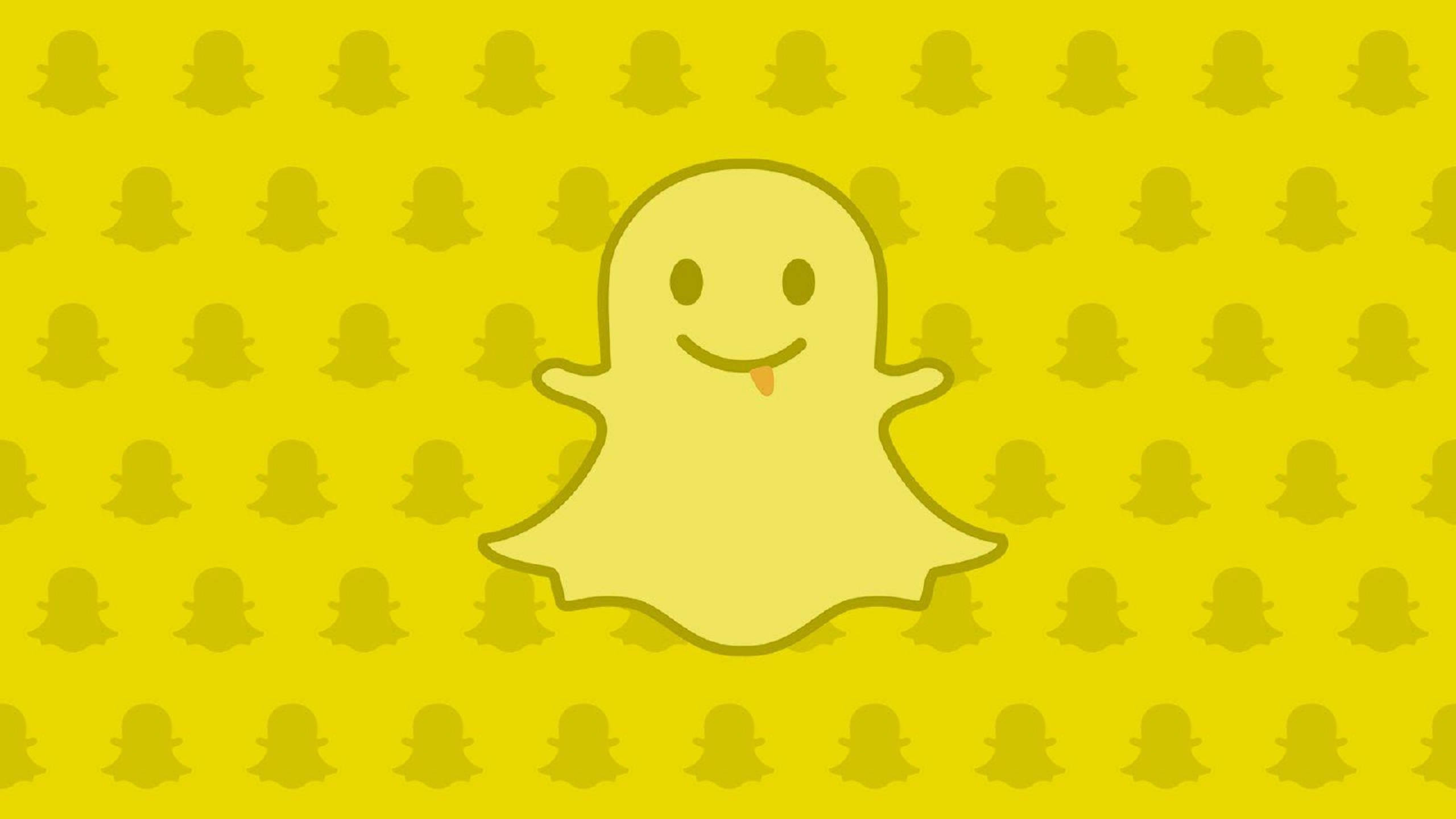 Snapchat黃色幽靈圖案 壁紙 — 一個伸出舌頭的開心黃色鬼魂漂浮在重複的鬼魂圖案上，背景為亮黃色。