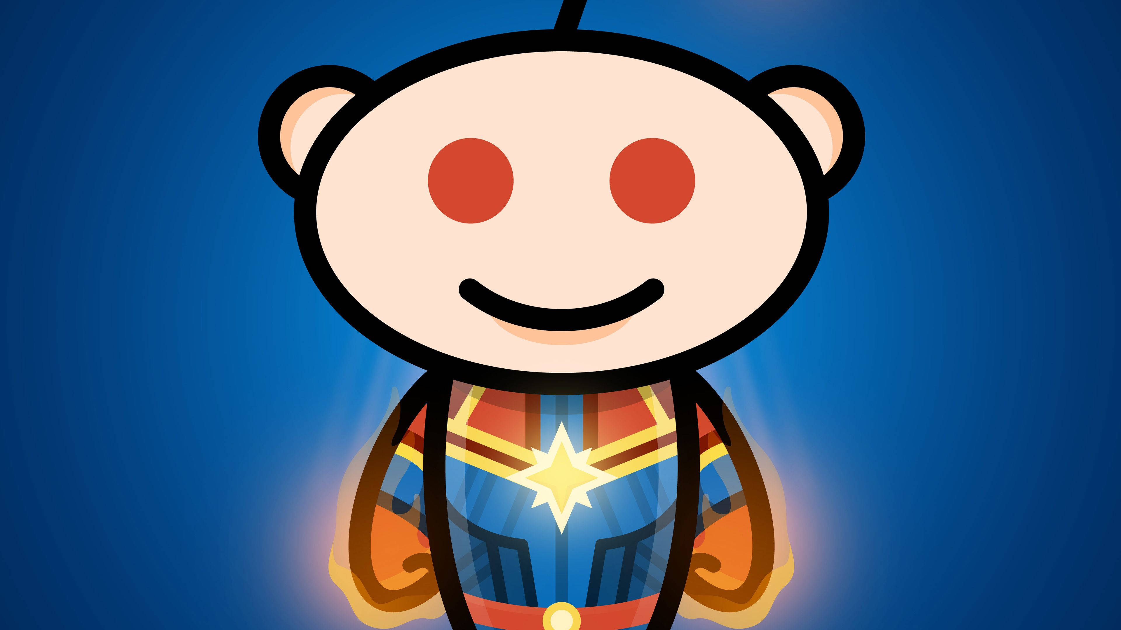 漫威隊長Snoo Reddit 壁紙 — 一個快樂的卡通外星人吉祥物，穿著超級英雄服裝，帶有發光的星星標誌，背景為藍色漸變。