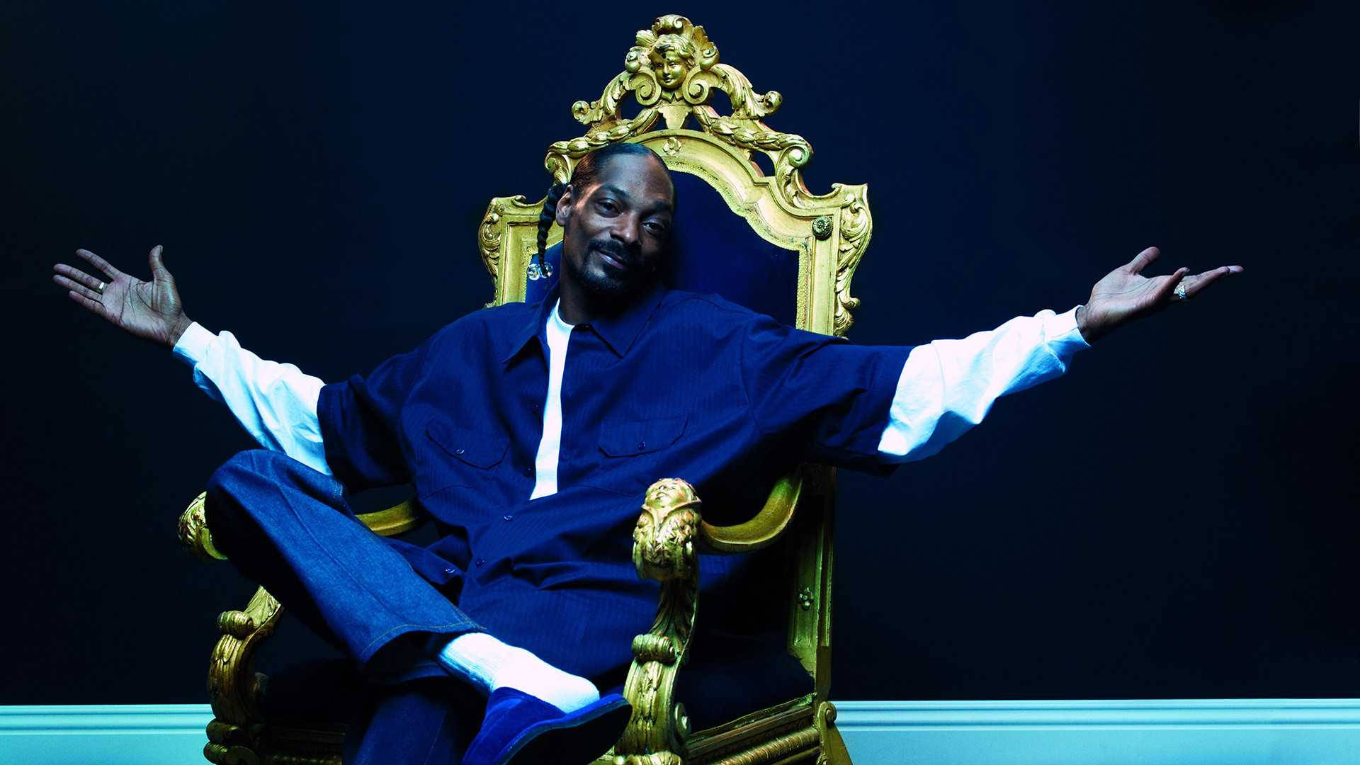 Snoop Dogg 坐在金鑾寶座上 壁紙 — Snoop Dogg 在黑暗背景下，雙臂大開，威嚴地坐在金色王座椅上。