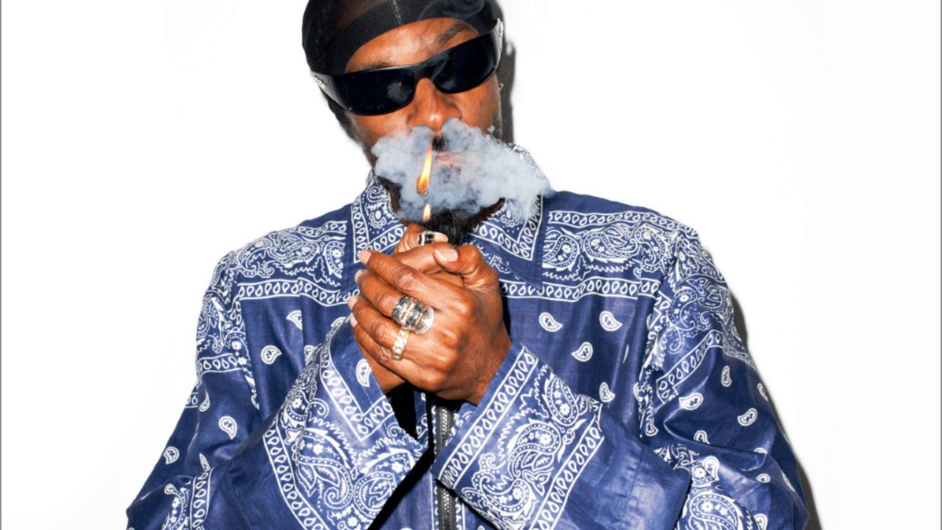 Snoop Dogg戴Crips藍色頭巾Polo衫 壁紙 — Snoop Dogg 身穿藍色佩斯利外套，在純白背景下手持點燃的大麻煙呼出煙霧。