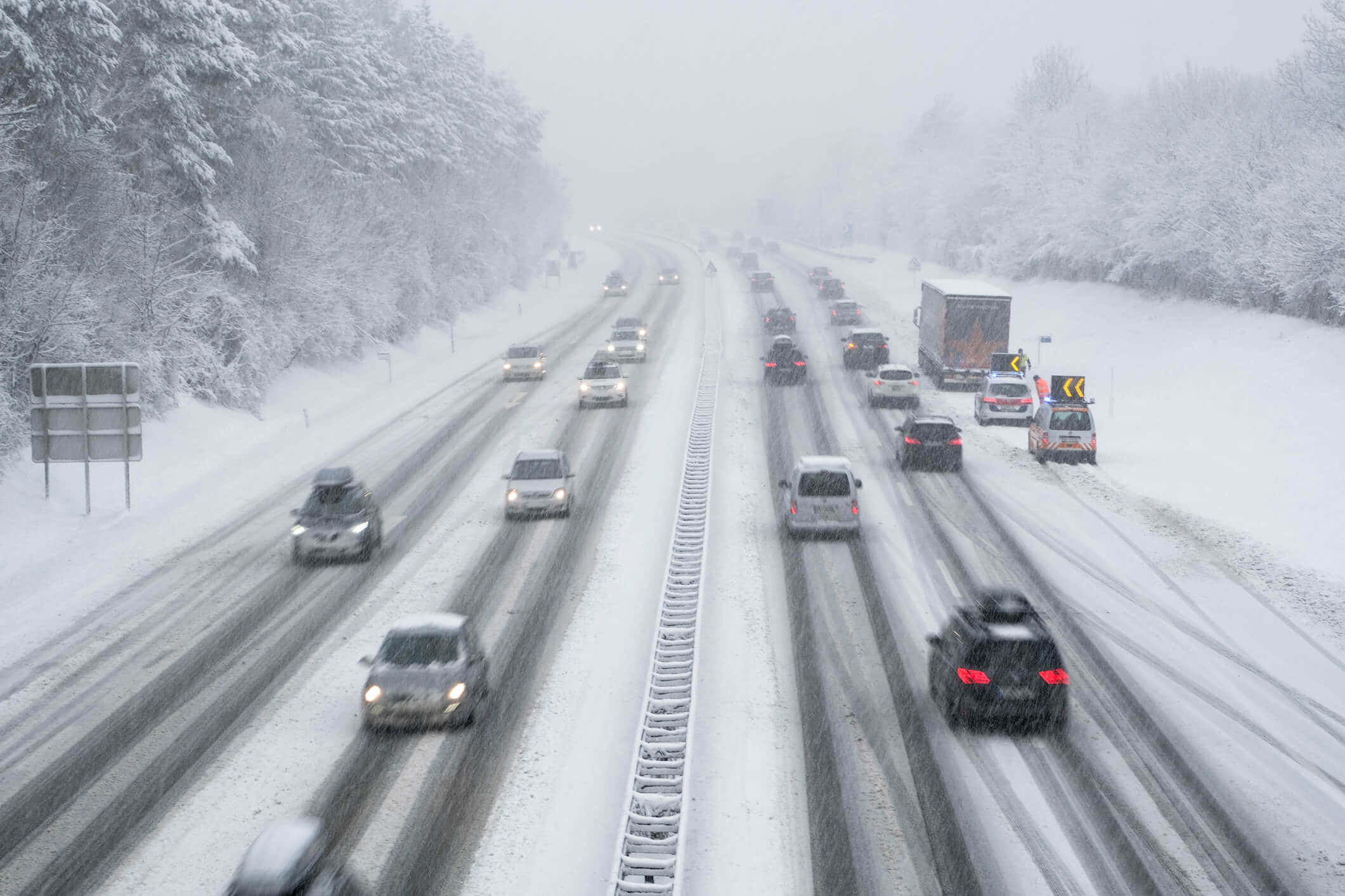 Winter Driving 桌布 壁紙 — 白雪覆蓋多線行車的高速公路，汽車在濃霧中行駛，車頭燈刺破白茫茫一片。