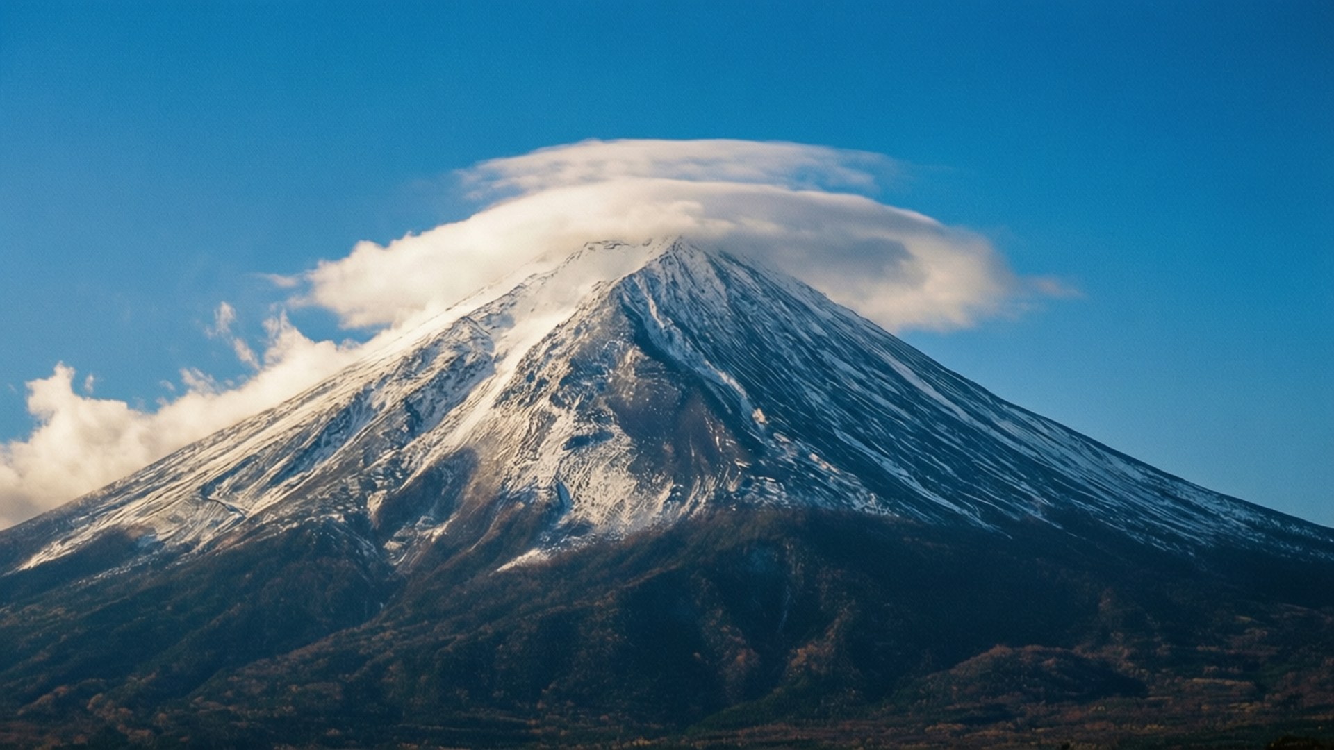 在清澈的藍天下，白雪覆蓋的富士山頂上有透鏡狀雲。