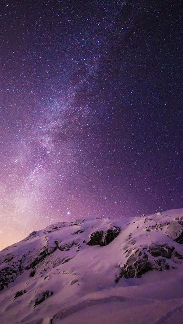  壁紙 — 被雪覆蓋的山脊，上方是充滿活力的紫色星空，銀河拱起。