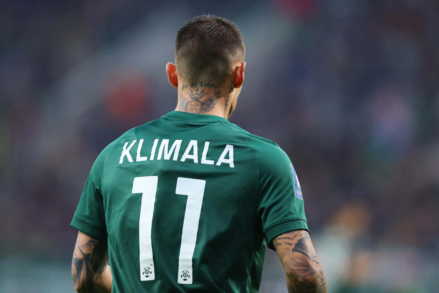  壁紙 — 一名身穿綠色球衣、印有名字KLIMALA和號碼11的足球員背對鏡頭站立，展示頸部和手臂上的紋身。
