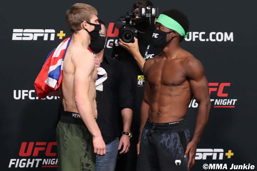 兩名戴著口罩的MMA拳手在UFC稱重活動中面對面站立。