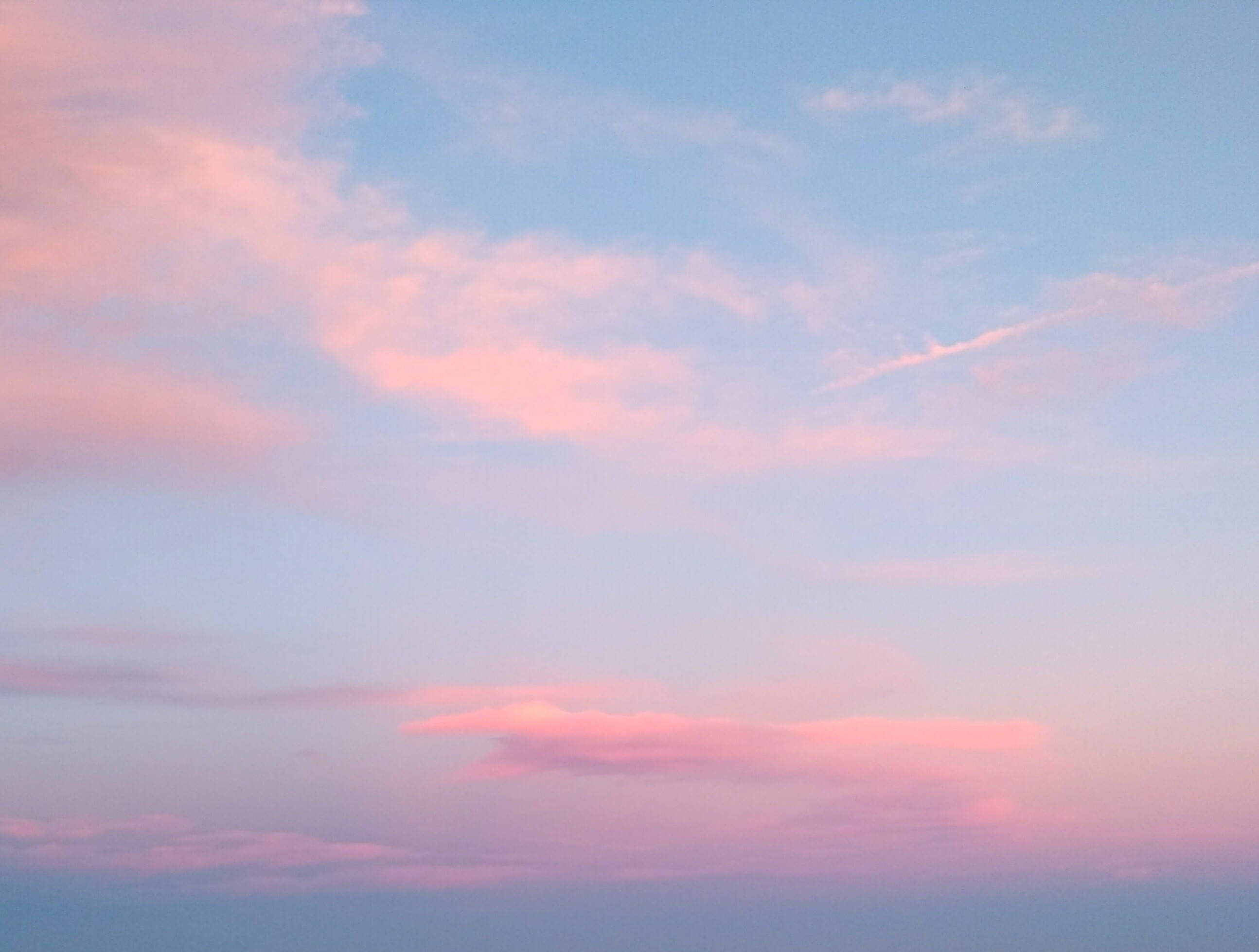 暮色寧靜天空 壁紙 — 柔和的粉紅色和藍色雲朵在寧靜的暮色天空中飄移，帶有淡淡的飛機尾跡。