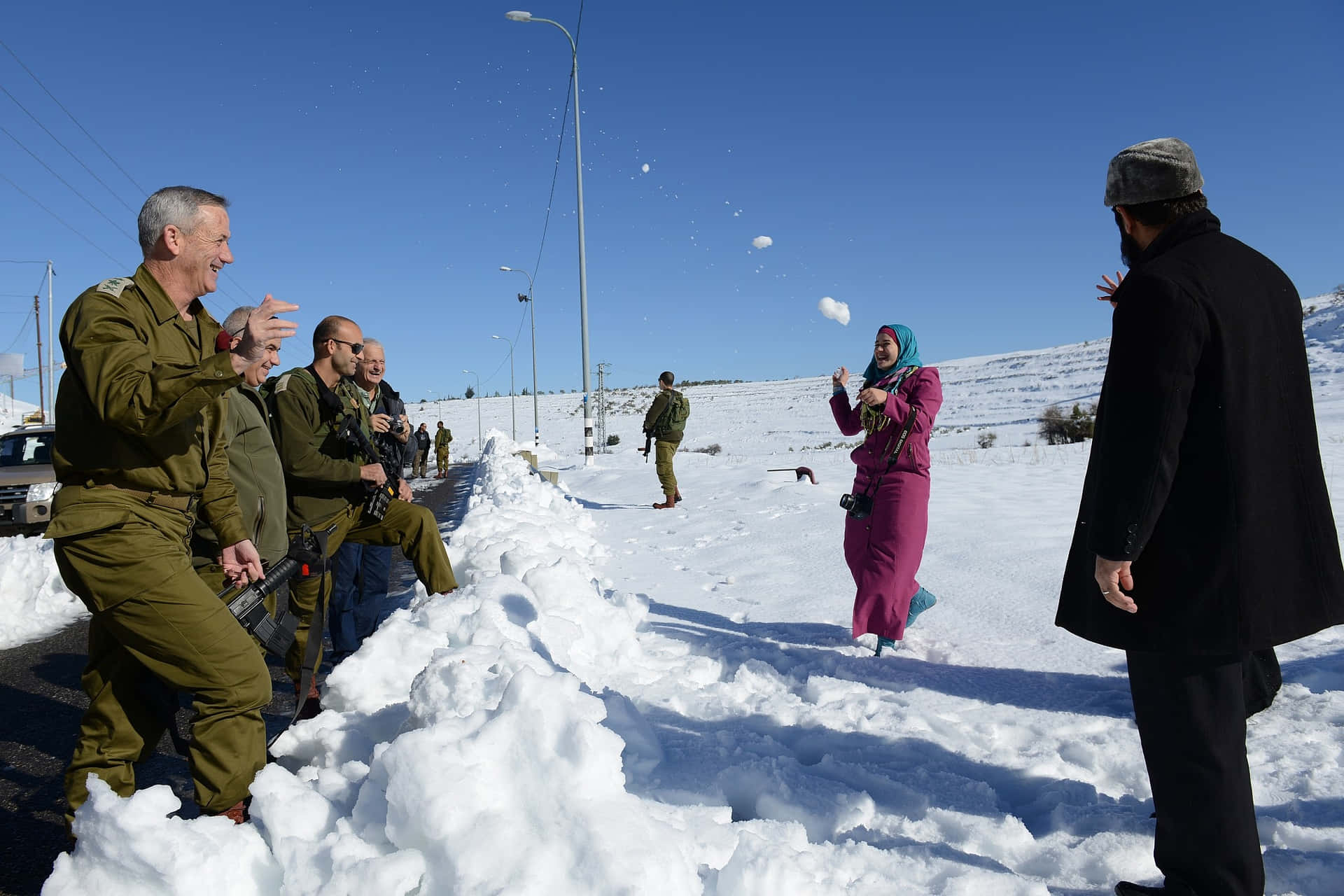  壁紙 — 士兵和市民在明亮陽光的冬日風景中開心地擲雪球。