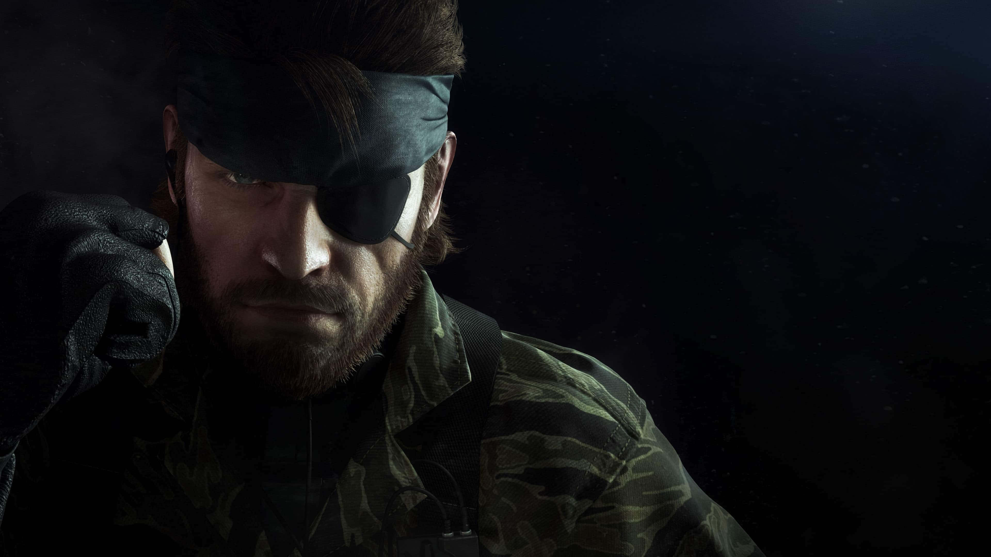 戴頭帶與眼罩的 Solid Snake 金屬戰爭 4K 壁紙 — 一個粗糙的特寫鏡頭，展示一位留鬍鬚、戴眼罩、身穿迷彩服的士兵，背景陰暗。