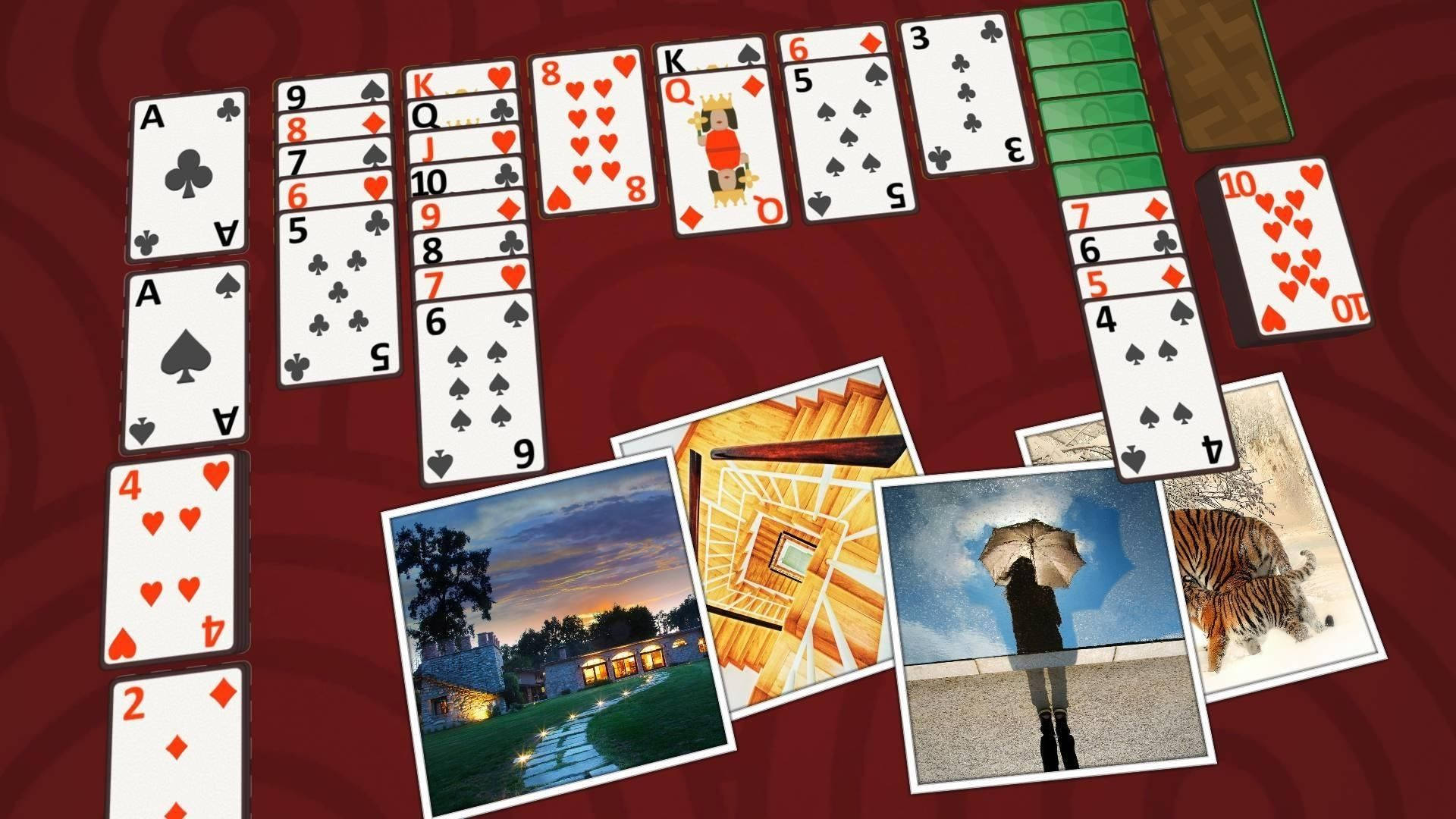 Solitaire 撲克牌與圖案 壁紙 — 鮮豔的紅色背景顯示散落的撲克牌和細小的照片，包括房子、日落、撐傘的人和老虎。