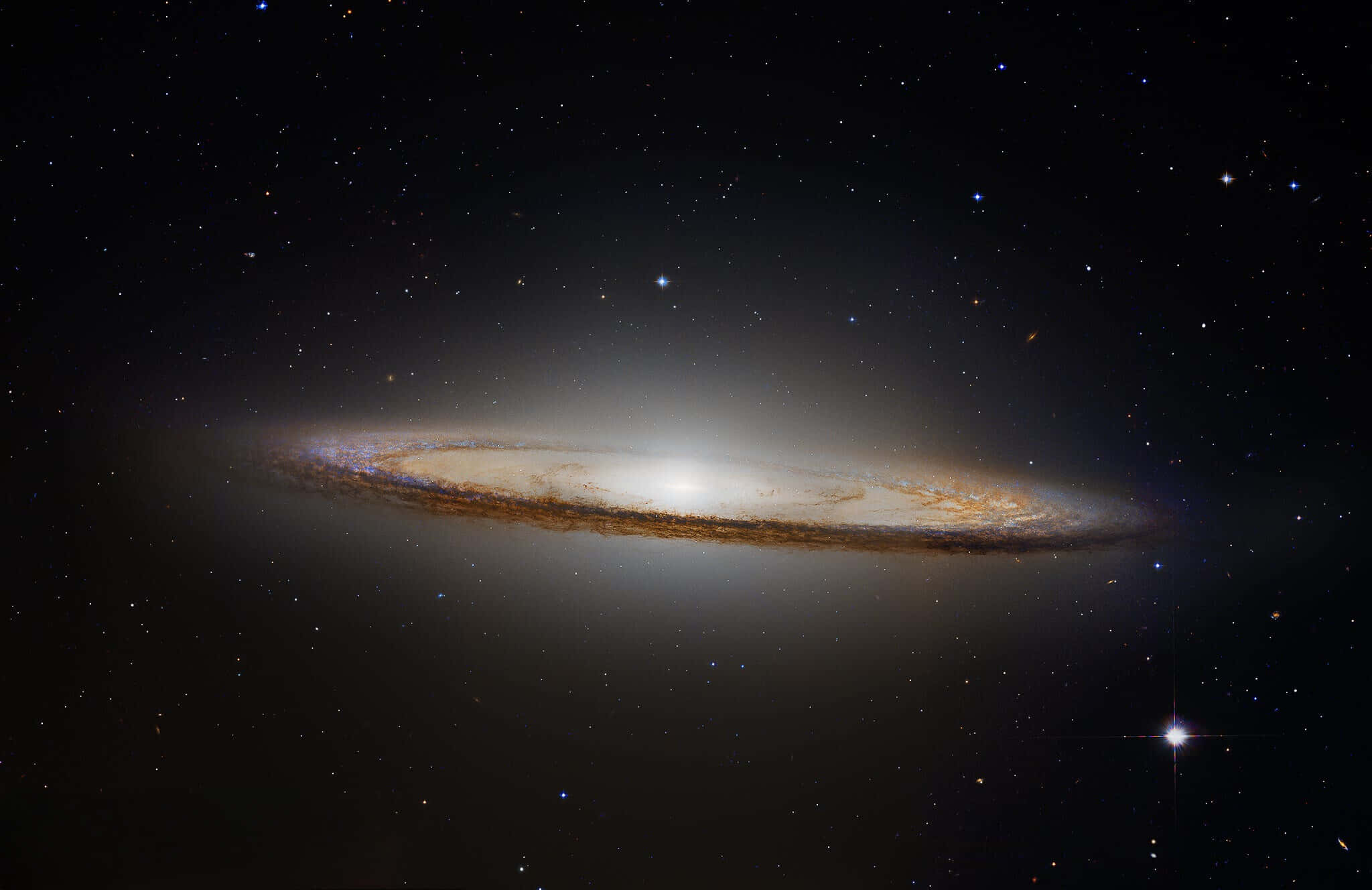 高解析度壯麗的 Sombrero 星系 壁紙 — 一個宏偉的螺旋星系在宇宙之夜中閃耀著金色塵埃帶，襯托著星場。