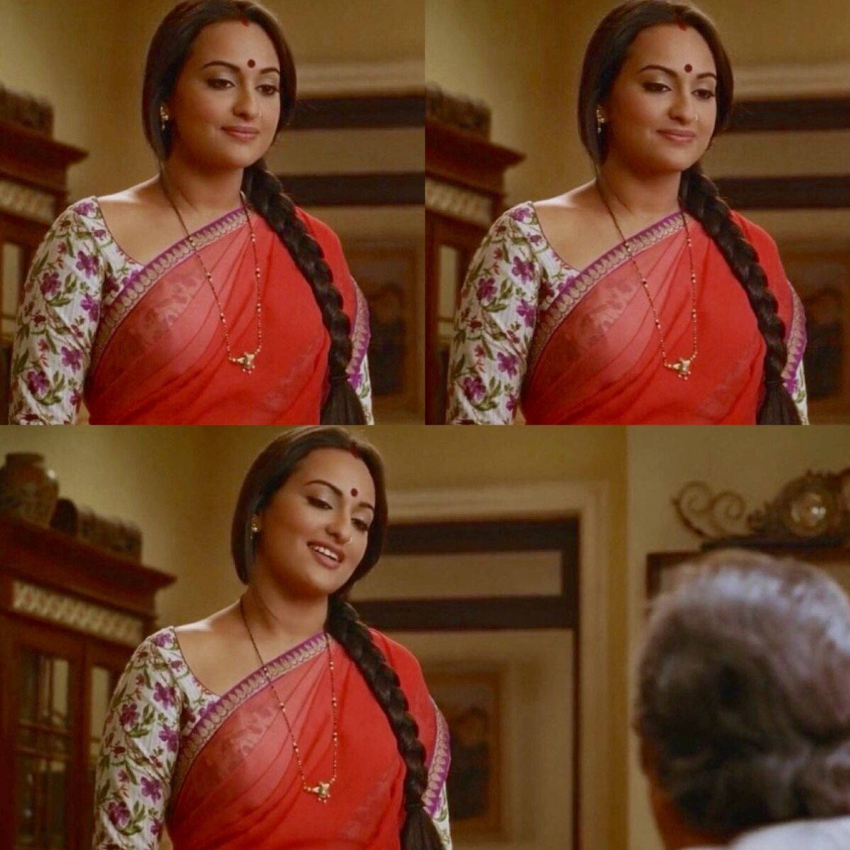 Sonakshi Sinha 演員形象 壁紙 — 一位身穿紅色花卉紗麗的女性在室內與一位年長者交談時溫暖地微笑。