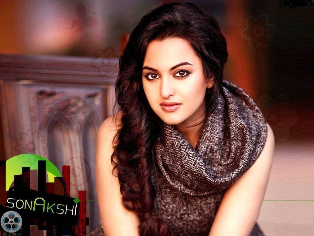 Sonakshi Sinha 的華麗造型 壁紙 — 一位擁有長深色波浪髮和質感圍巾的女性，在柔和光線下直視鏡頭。