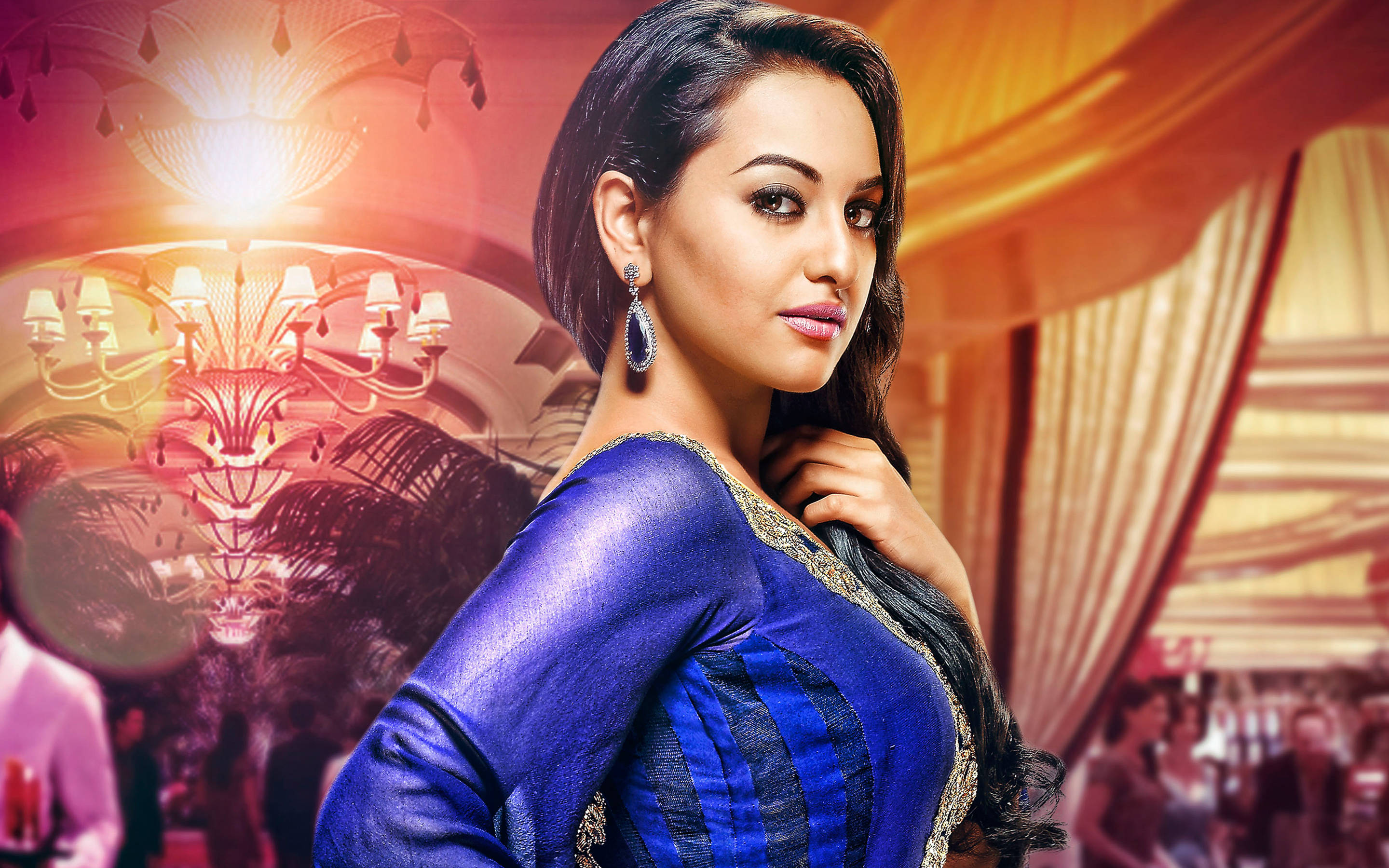 Sonakshi Sinha 紫色優雅禮服 壁紙 — 一位身穿皇家藍色紗麗的迷人女性，在豪華金色宴會廳閃爍的水晶燈下自信地擺姿勢。