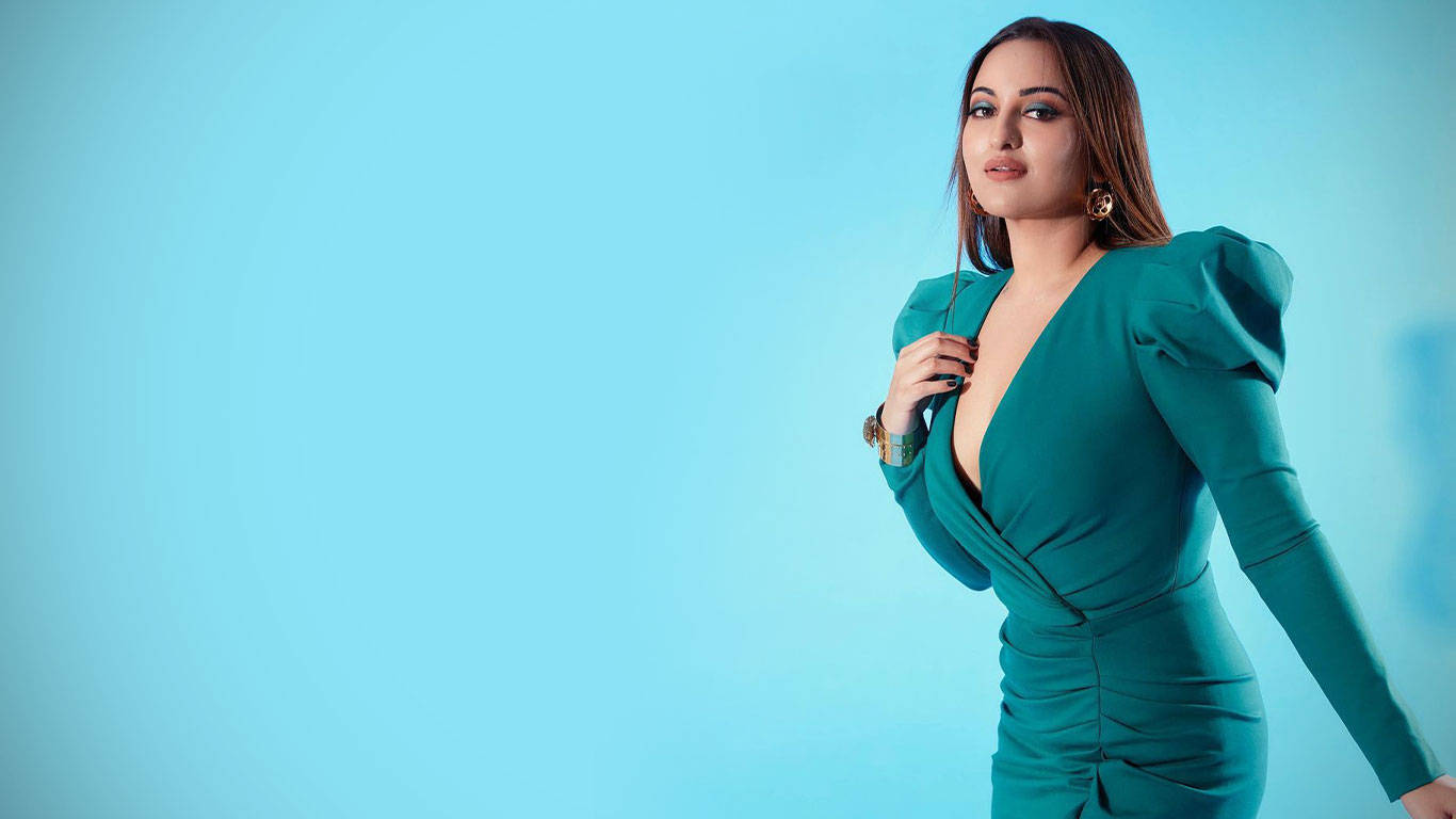 Sonakshi Sinha 綠色時尚洋裝 壁紙 — 一位身穿青綠色連衣裙的女性在純色淺藍色攝影棚背景前自信地擺姿勢。