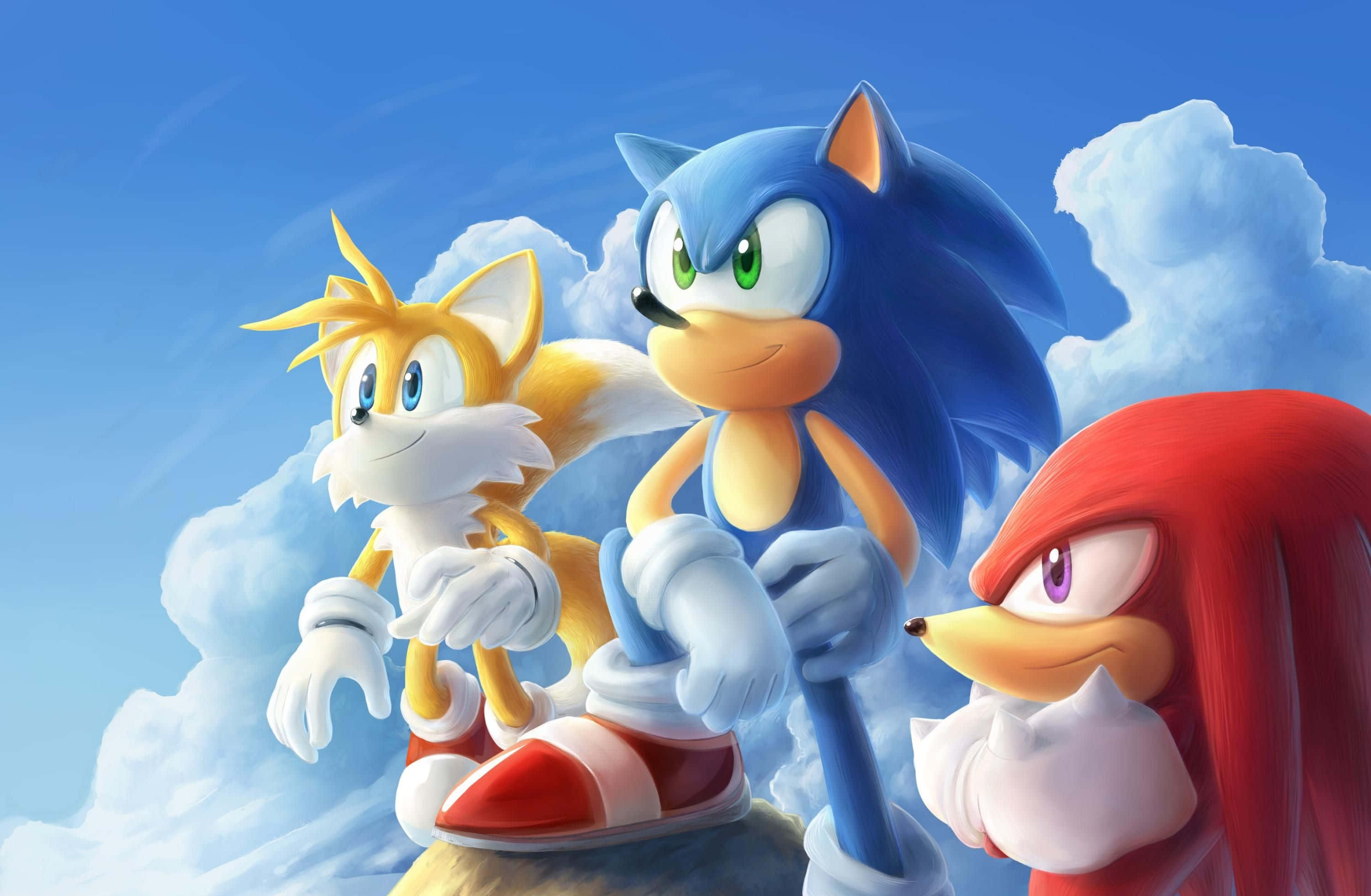 「Sonic 2 證明是原作後最需要的續作。」 壁紙 — Sonic Tails 和 Knuckles 一起站在岩石露頭上，背景是明亮的藍天和蓬鬆的白雲。
