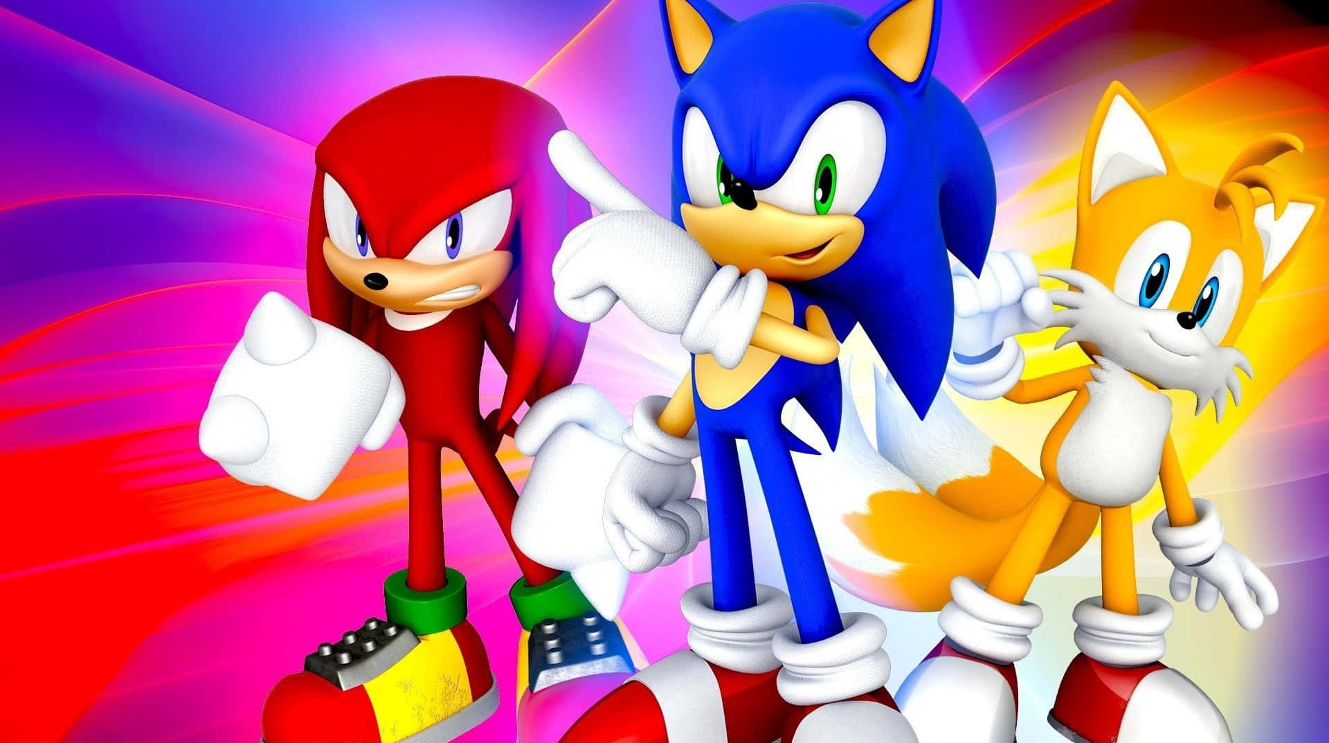 Sonic And Tails 桌布 壁紙 — Sonic、Knuckles 和 Tails 在充滿活力的紅、紫、黃色條紋背景上動態擺姿勢。