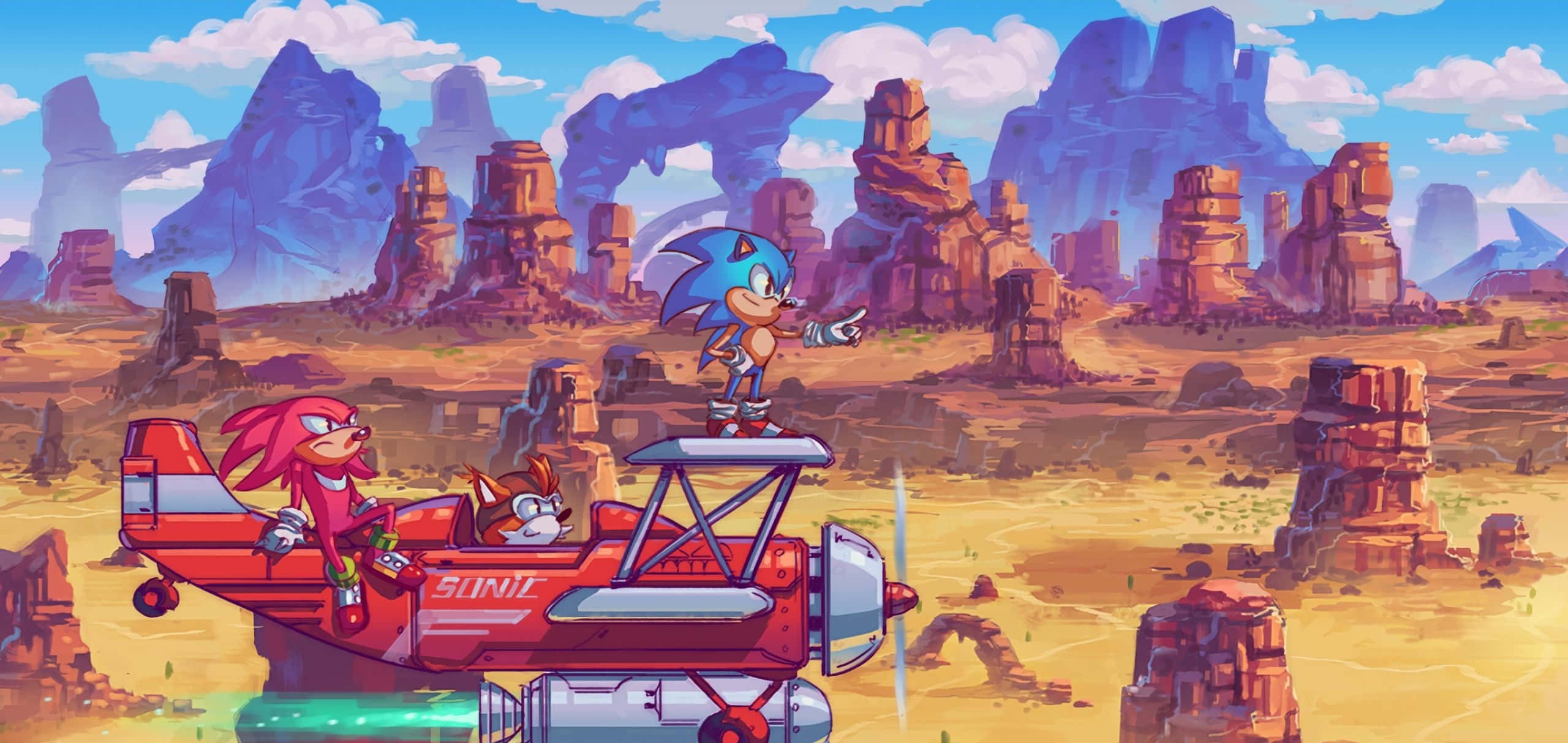 Sonic Angel Island 桌布 壁紙 — Sonic the Hedgehog 企喺一架由 Knuckles 同 Tails 揸嘅紅色飛機上面，飛過一個有岩石形成嘅沙漠峽谷。