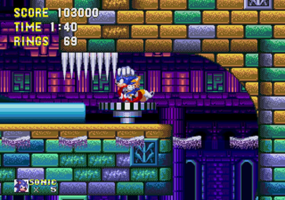 Sonic Hydrocity Zone 桌布 壁紙 — Sonic the Hedgehog 站在一個像素化的城堡關卡中的基座上，周圍有色彩繽紛的磚牆和天花板上懸掛的冰柱。