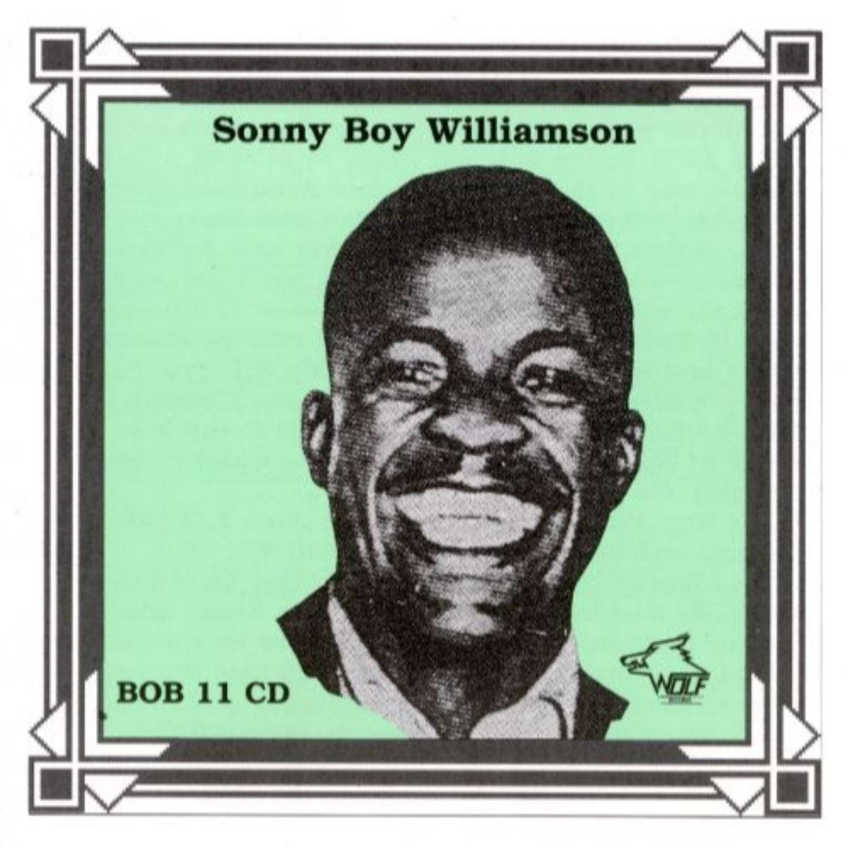 Sonny Boy Williamson I 美國藍調 壁紙 — 一幅歡樂的黑白半色調肖像，Sonny Boy Williamson 在薄荷綠色背景上微笑，帶有裝飾邊框。