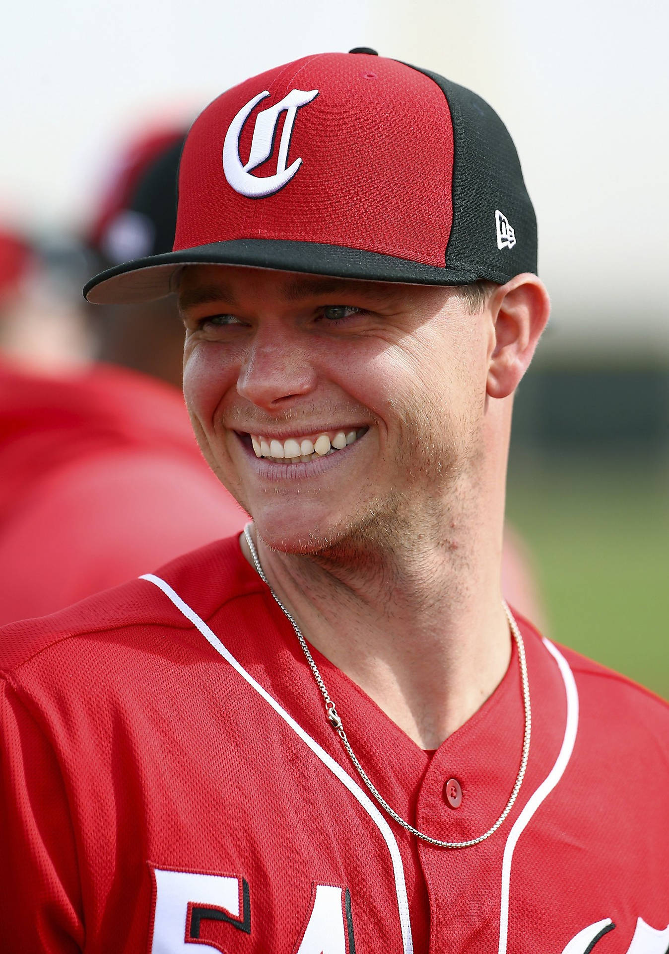 Sonny Gray 大笑 壁紙 — 一位身穿紅色球衣和帽子的微笑棒球運動員在陽光明媚的日子裡對著鏡頭綻放笑容。