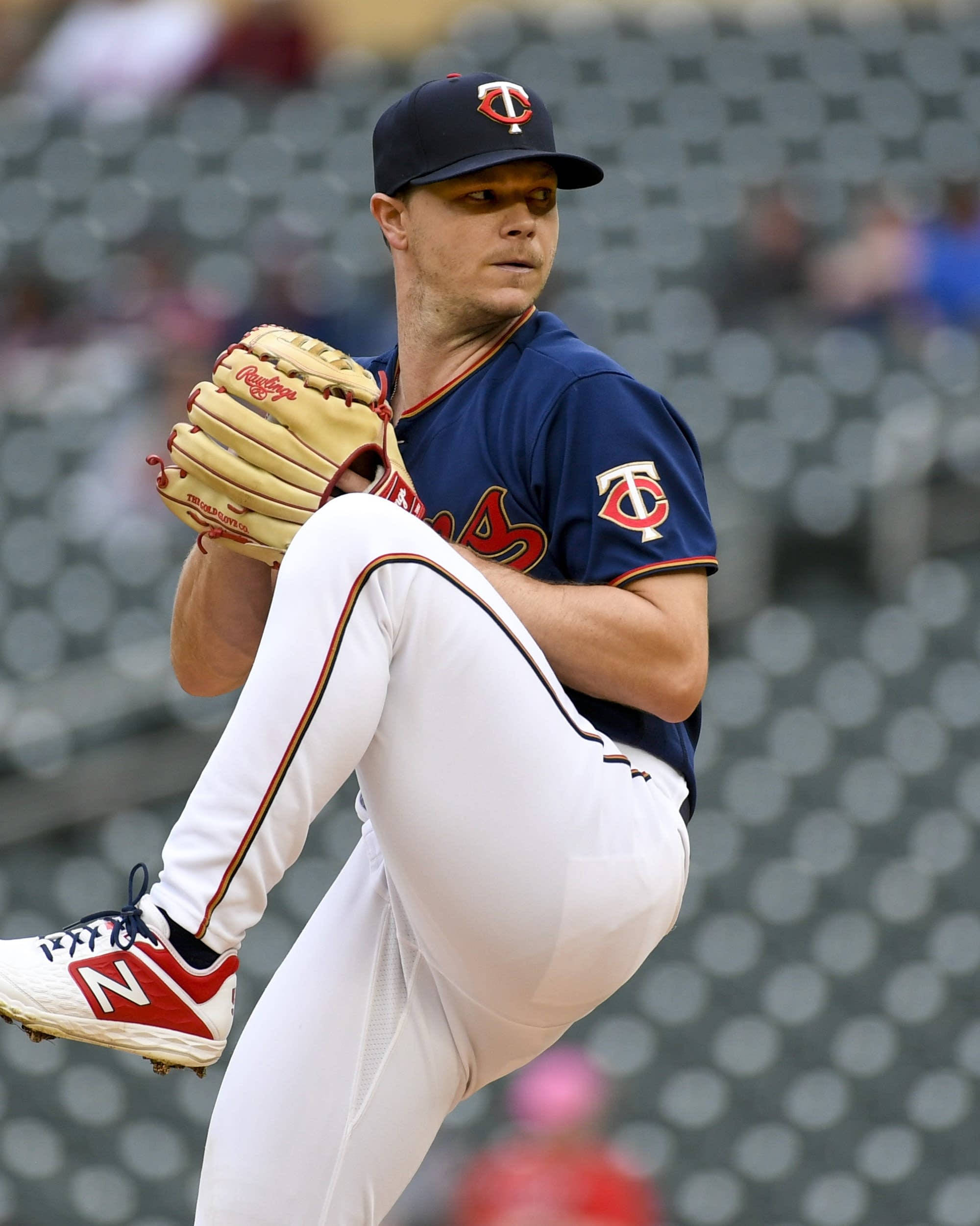 Sonny Gray 投球姿勢 壁紙 — 一名身穿明尼蘇達雙城隊球衣的棒球投手，在模糊的球場背景下專注地投球。