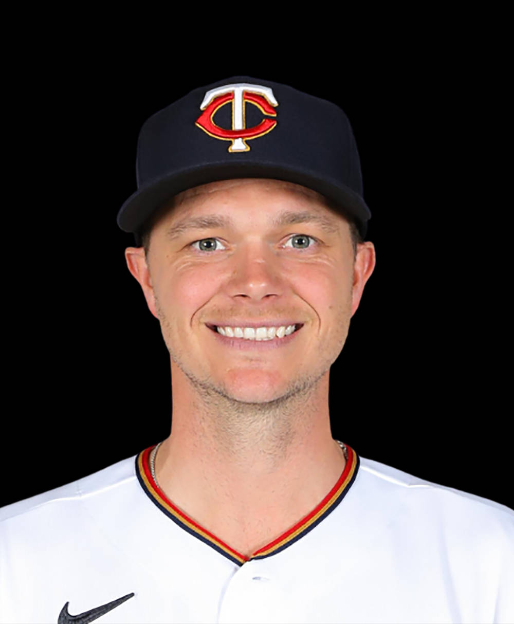 Sonny Gray 獨照 壁紙 — 一位微笑的棒球運動員，身穿白色制服，戴著帶有紅色和金色TC標誌的海軍藍帽子，背景為黑色。
