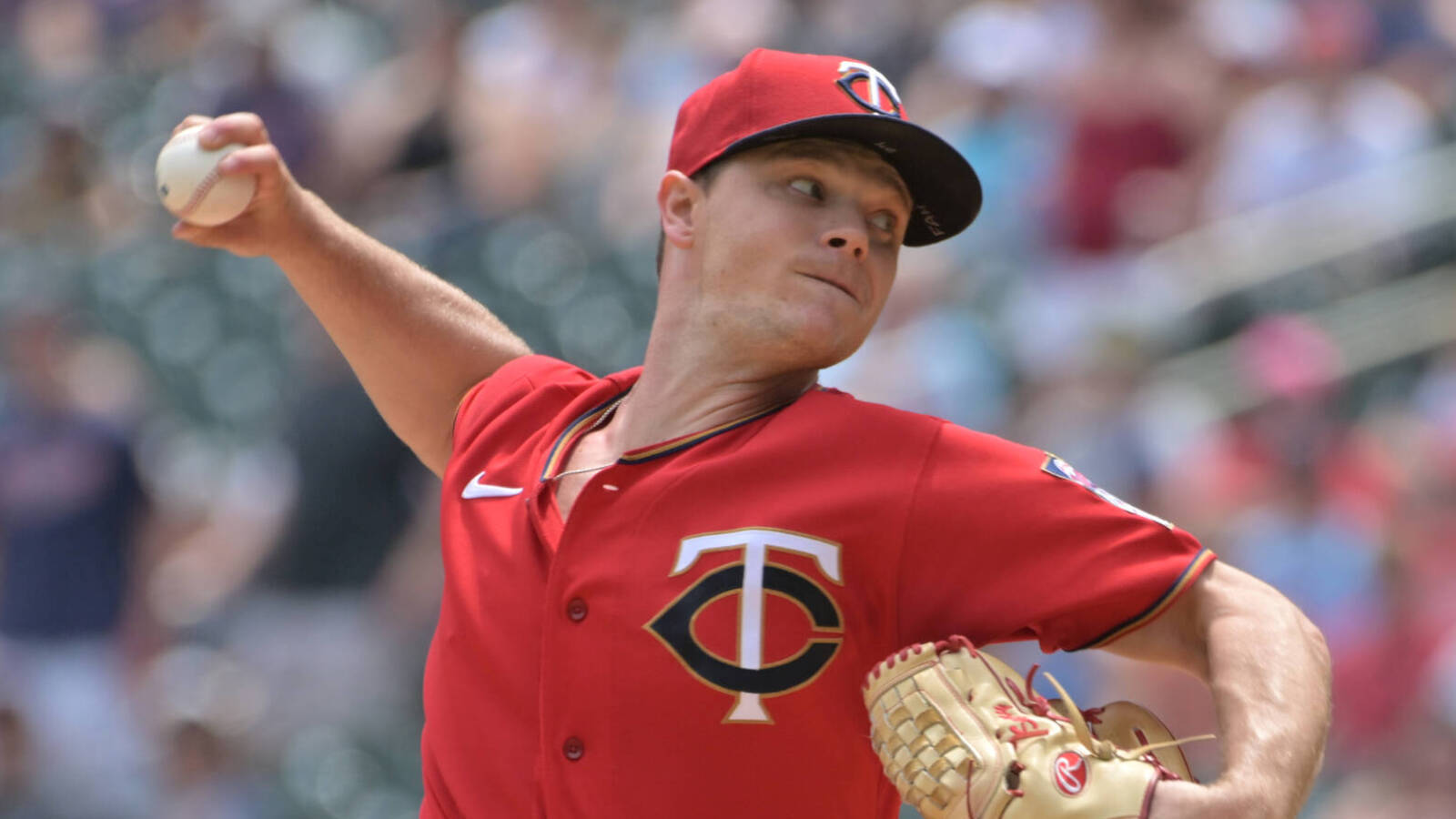 Sonny Gray 賽場專注模樣 壁紙 — 一名身穿紅色明尼蘇達雙城隊球衣的棒球投手，在日間比賽中準備投球，背景是模糊的體育場人群。